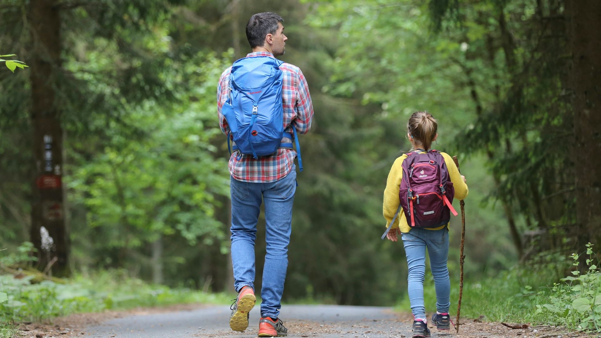 man in blue jacket and blue denim jeans walking on dirt road during daytime