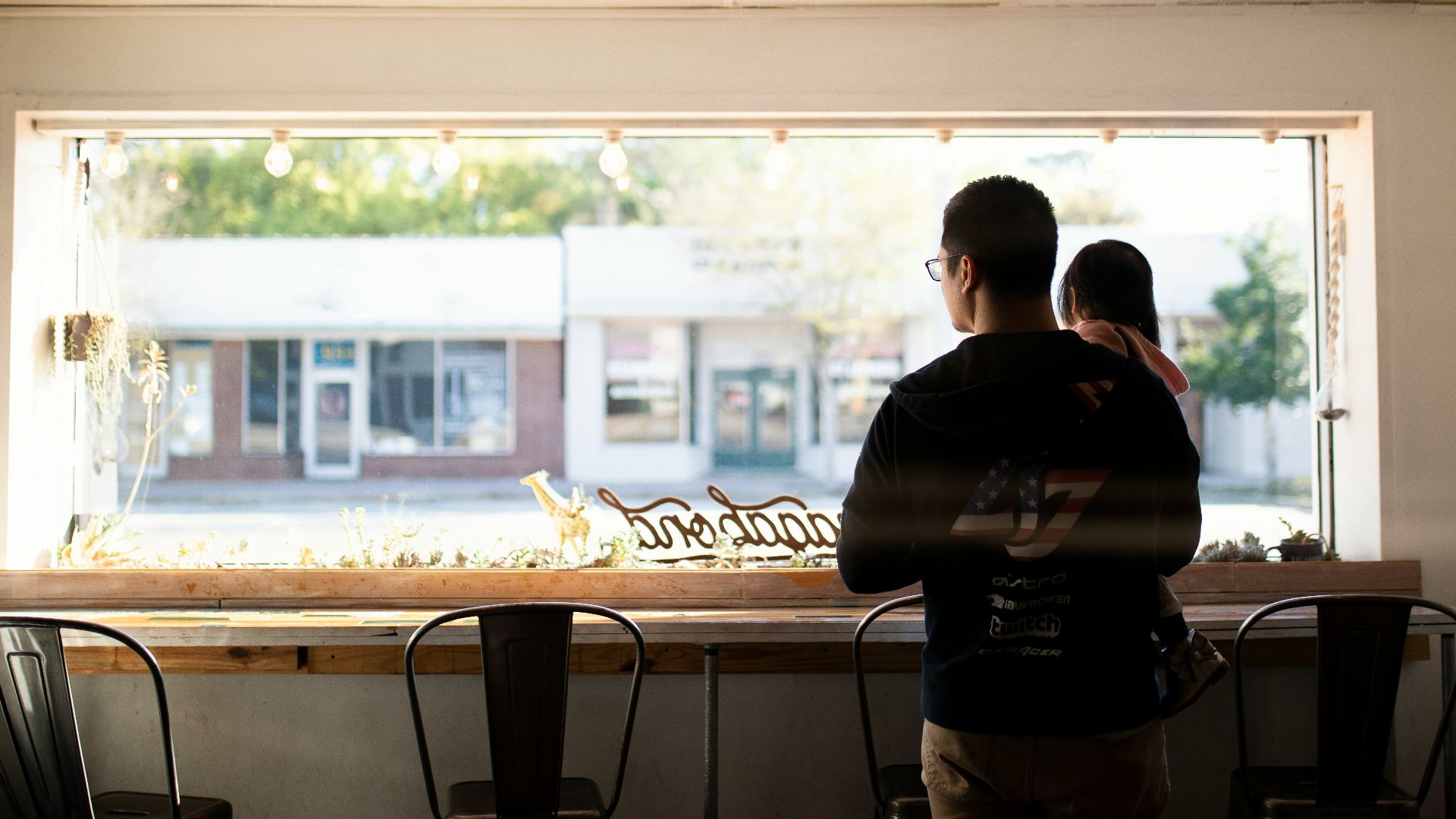 man carrying child looking through window during daytime