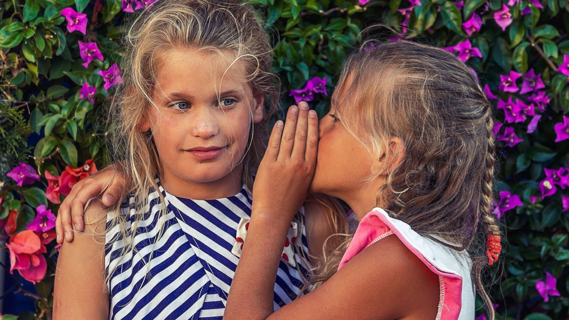 girl in white shirt kissing girl in blue and white stripe shirt