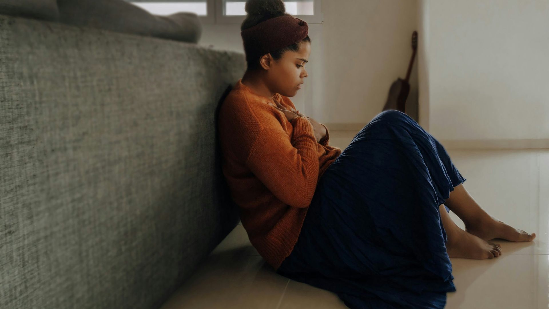 man in orange long sleeve shirt sitting on gray couch