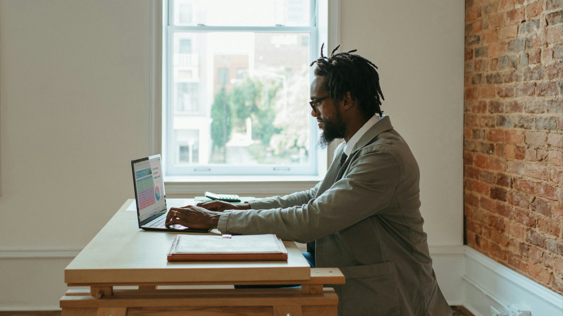 a person sitting at a desk with a laptop and papers