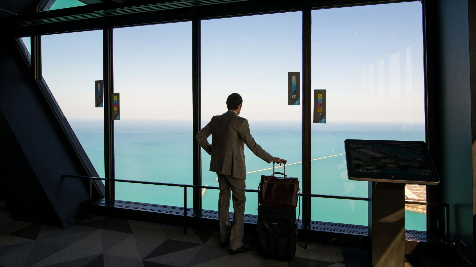man in white shirt standing near glass window