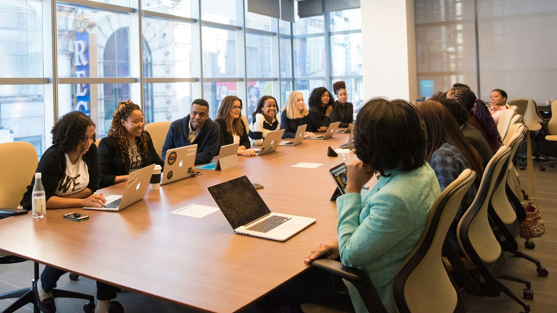 group of people sitting beside rectangular wooden table with laptops