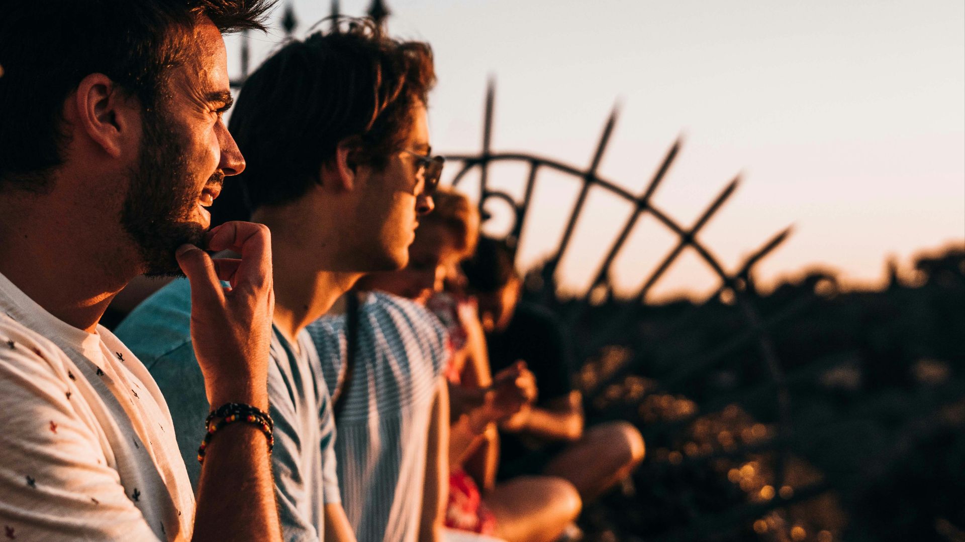 man sitting on fence facing right way under golden hour