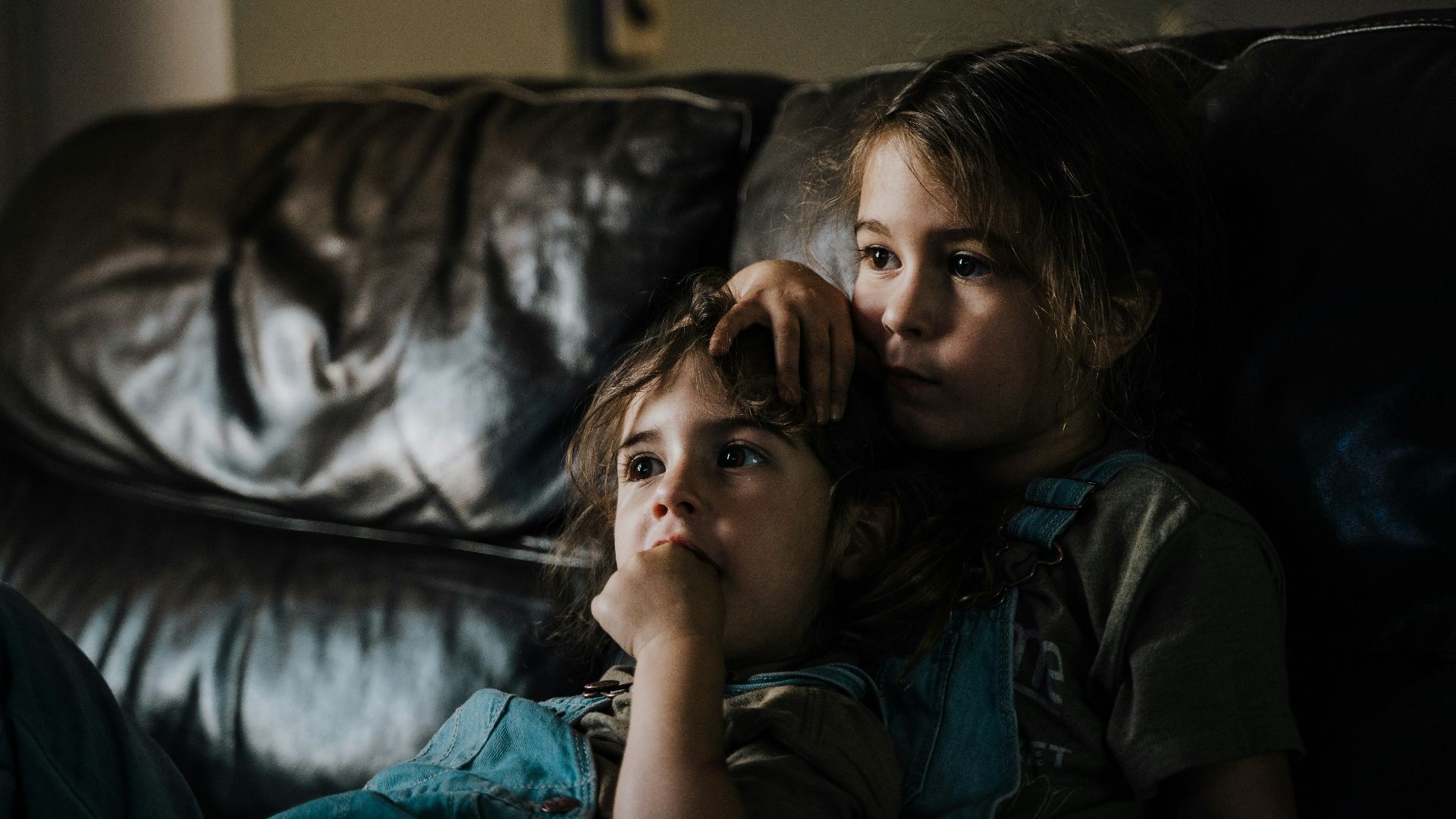 girl in black and gray camouflage shirt lying on black leather couch