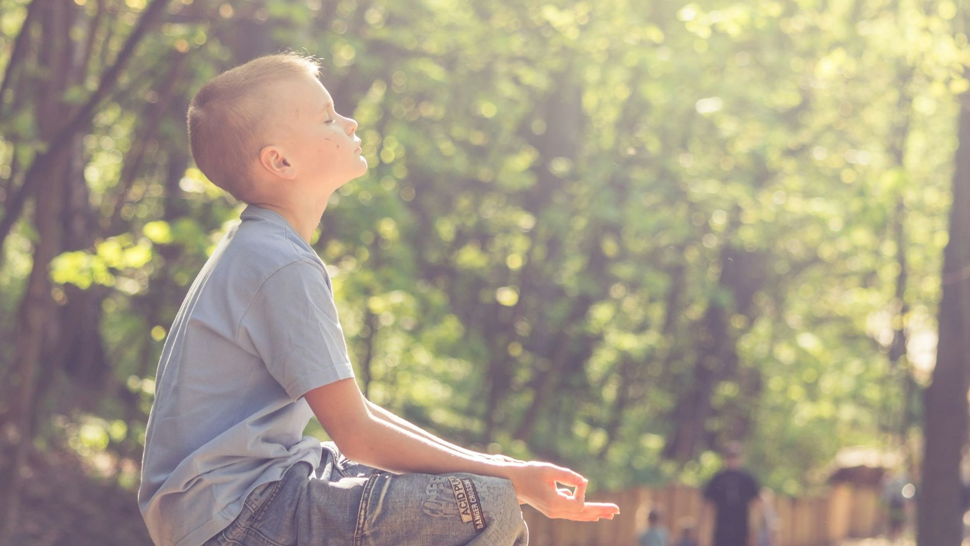 man in blue t-shirt and brown pants sitting on brown wooden seat during daytime