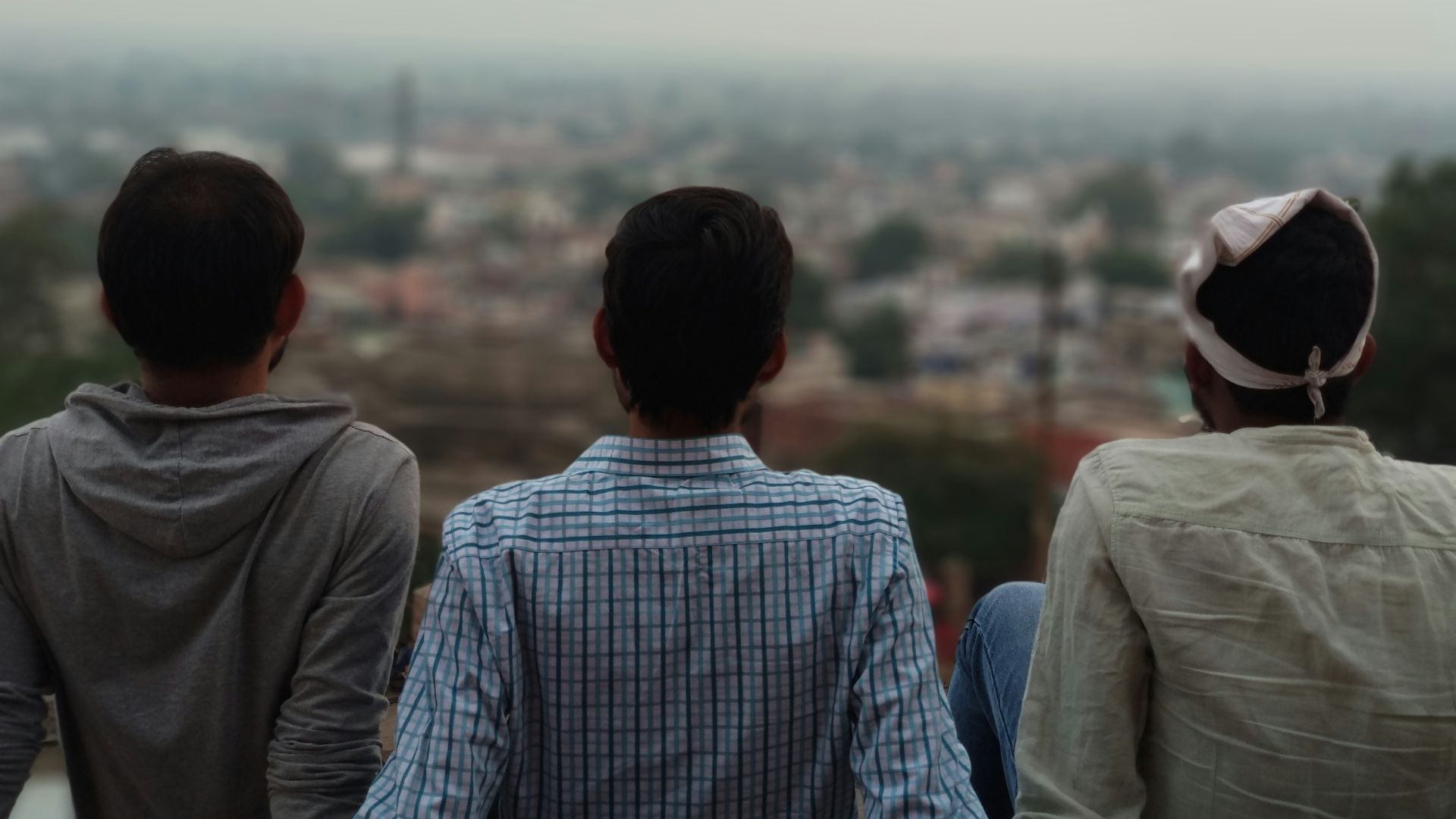three man sitting on top of building