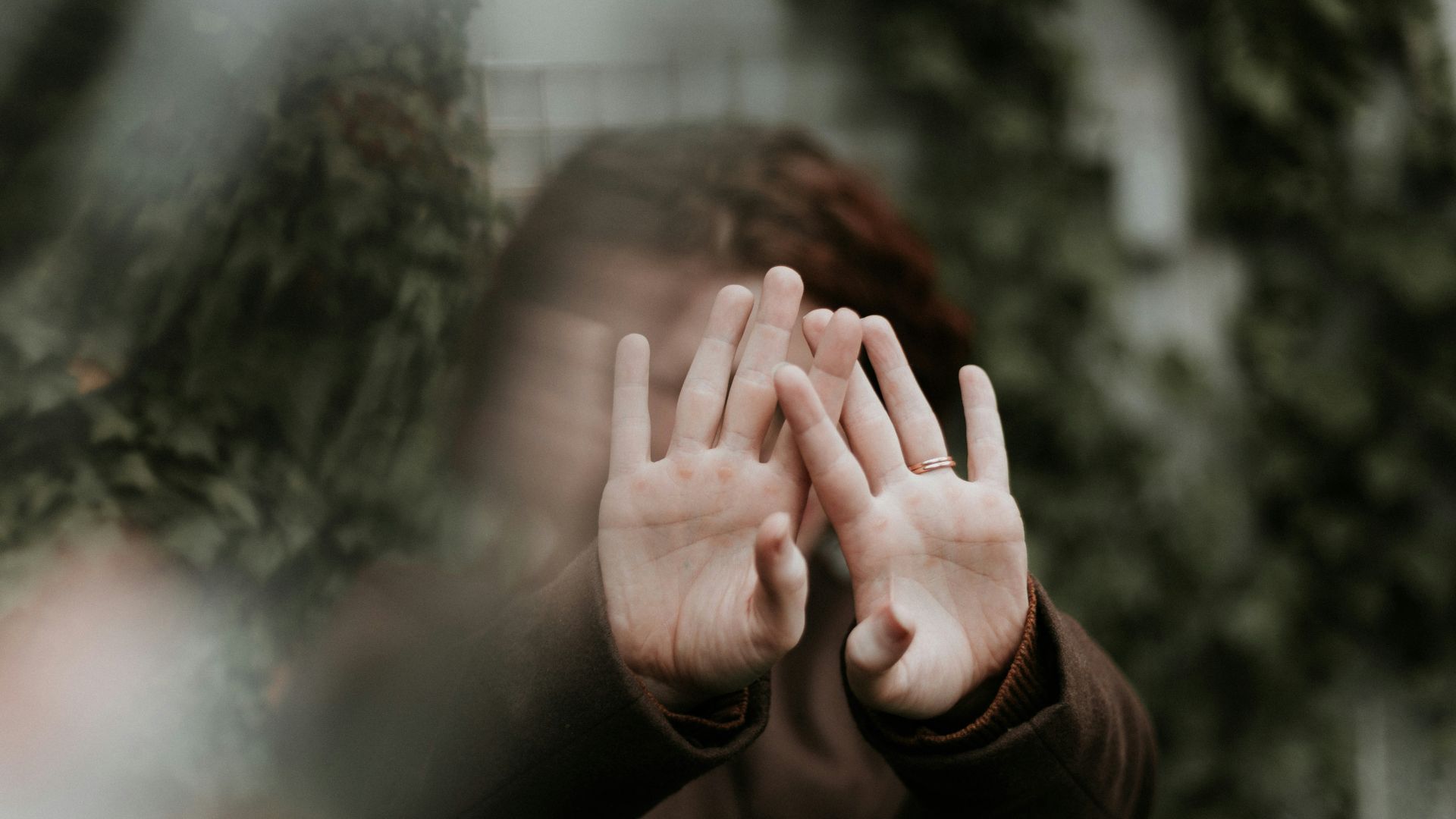 person in brown long sleeve shirt covering face with hand