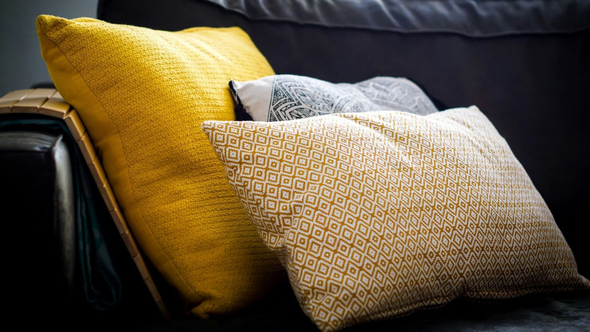 three assorted-color throw pillows on black sofa
