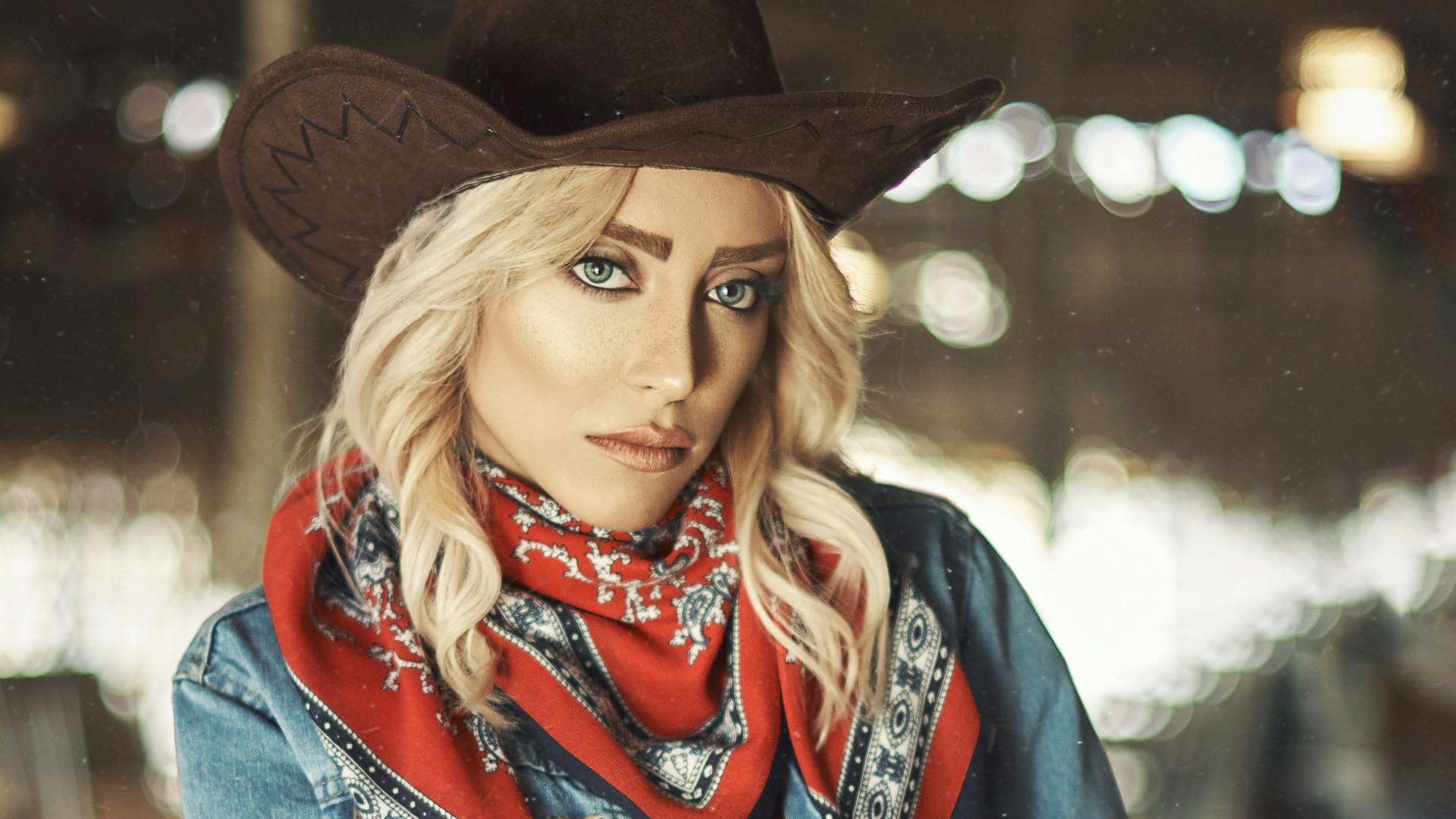 woman in blue denim jacket and black cowboy hat holding brown wooden cup
