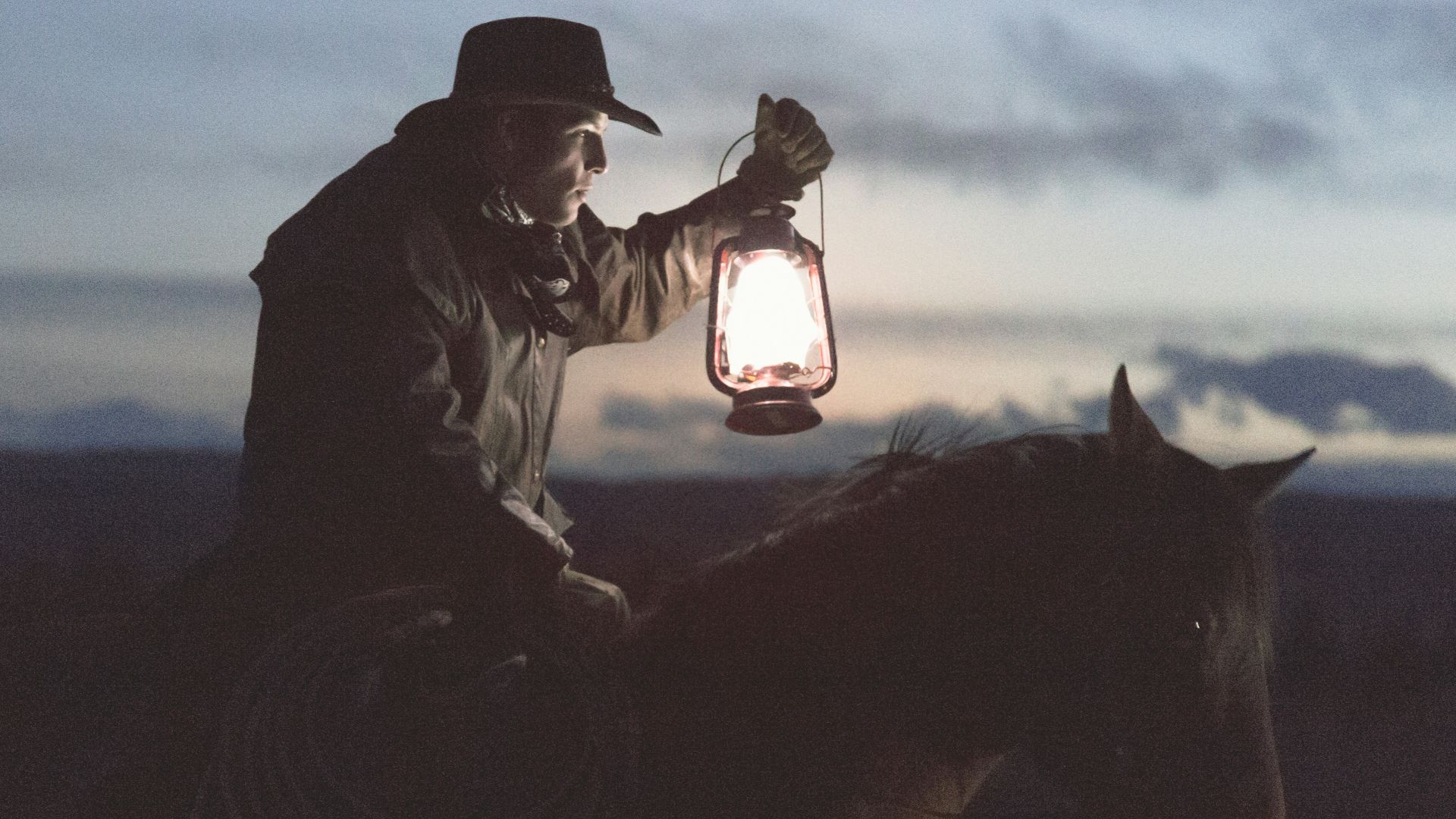 man riding horse holding lantern