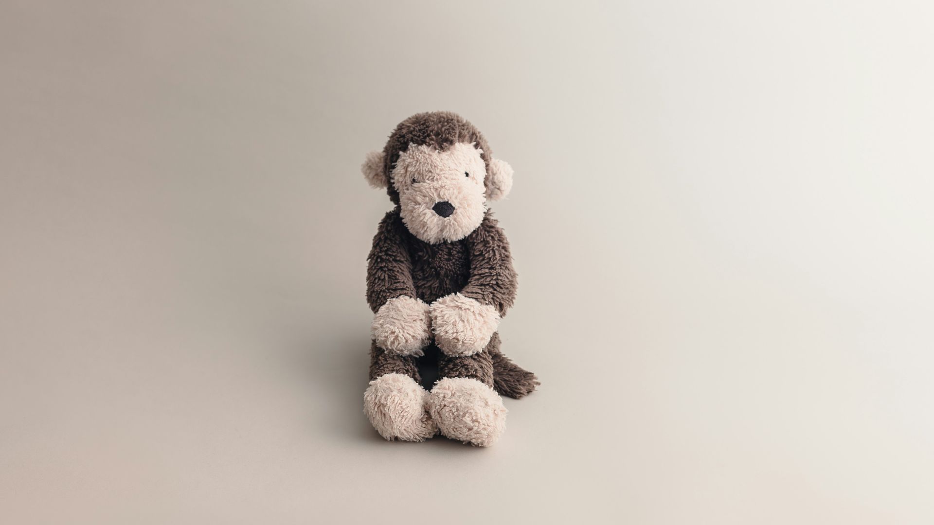 a stuffed monkey sitting on a white surface
