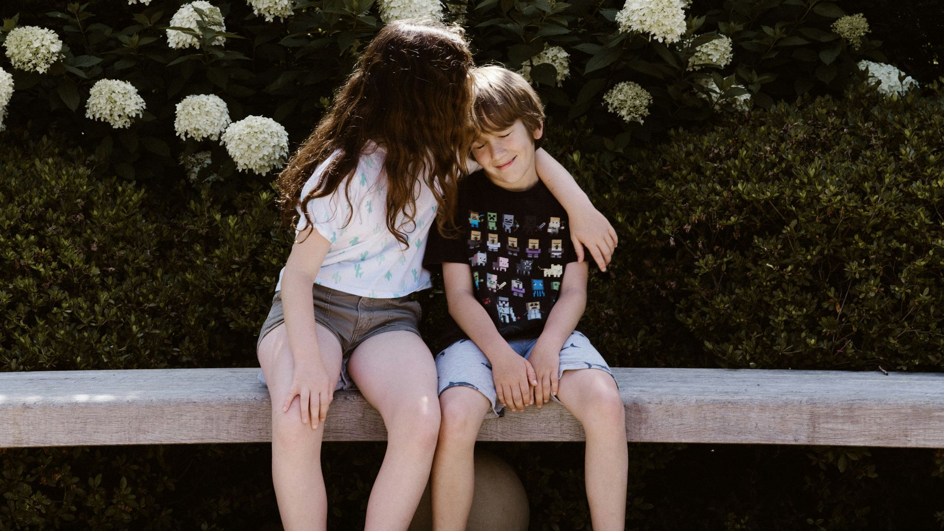 two toddler girl and boy sitting on concrete bench near outdoor during daytime