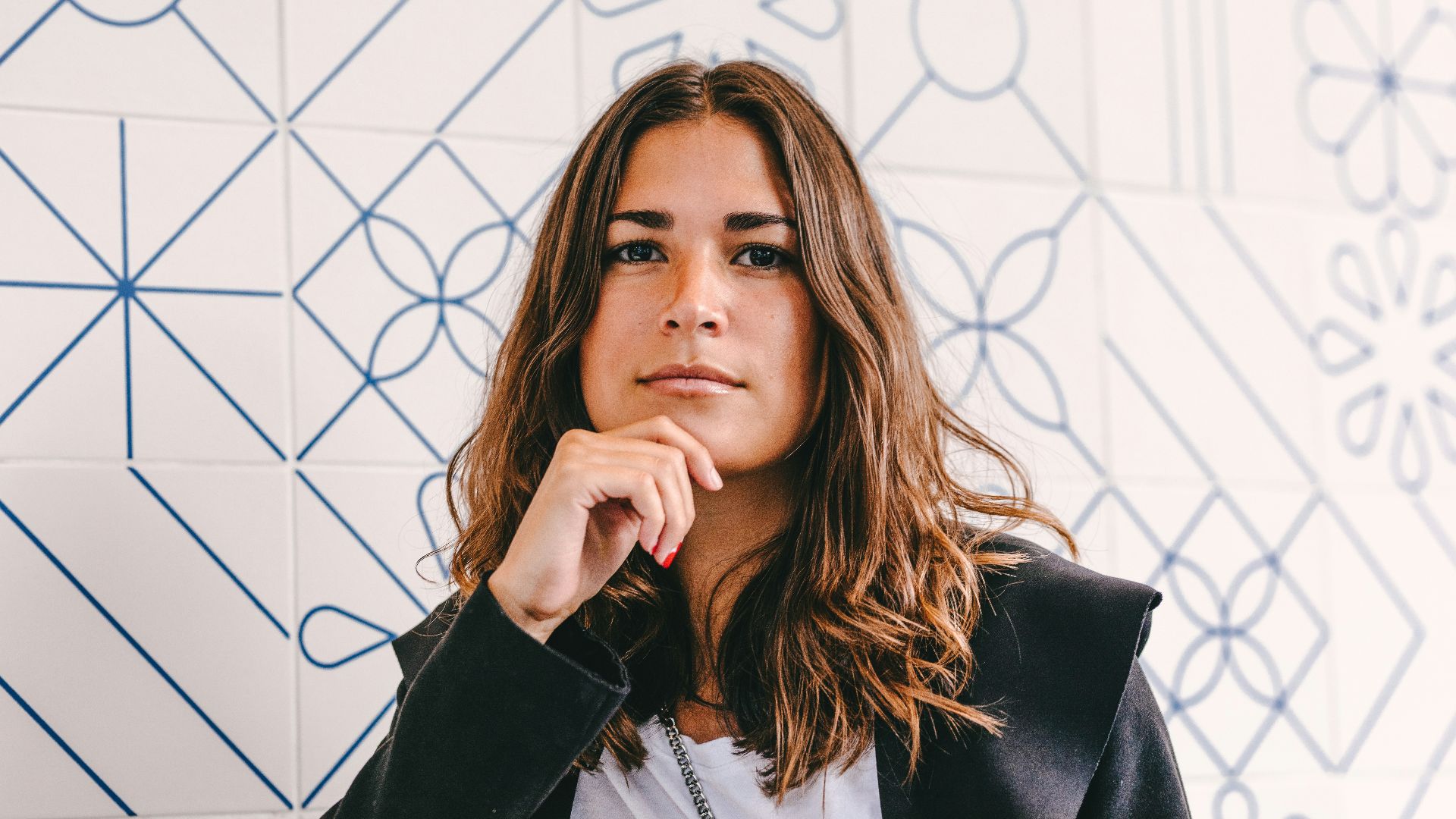 woman in black blazer covering her face with her hand