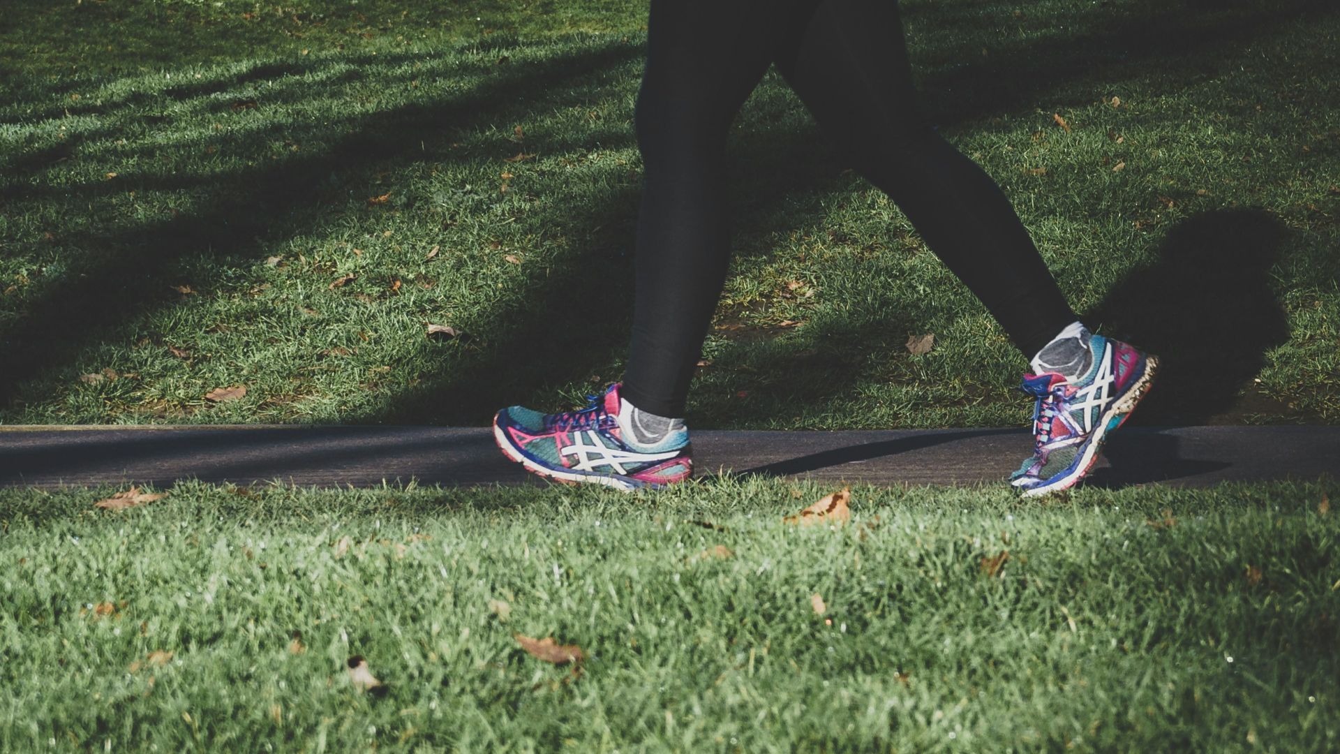 shallow focus photography of person walking on road between grass
