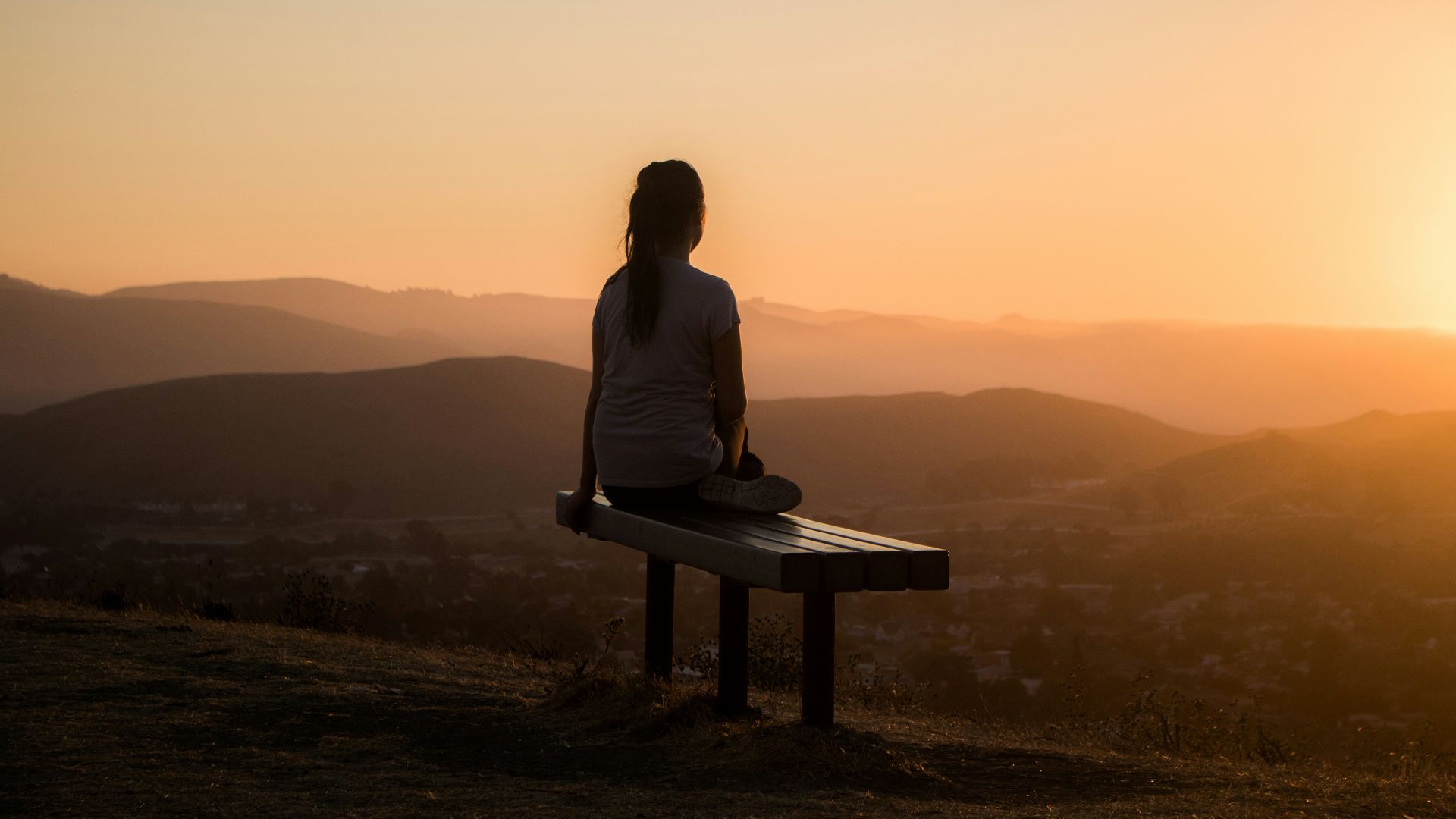 woman sitting on bench over viewing mountain