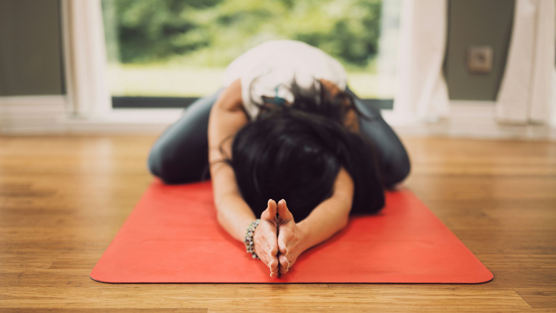 woman in white shirt lying on red mat on brown wooden table