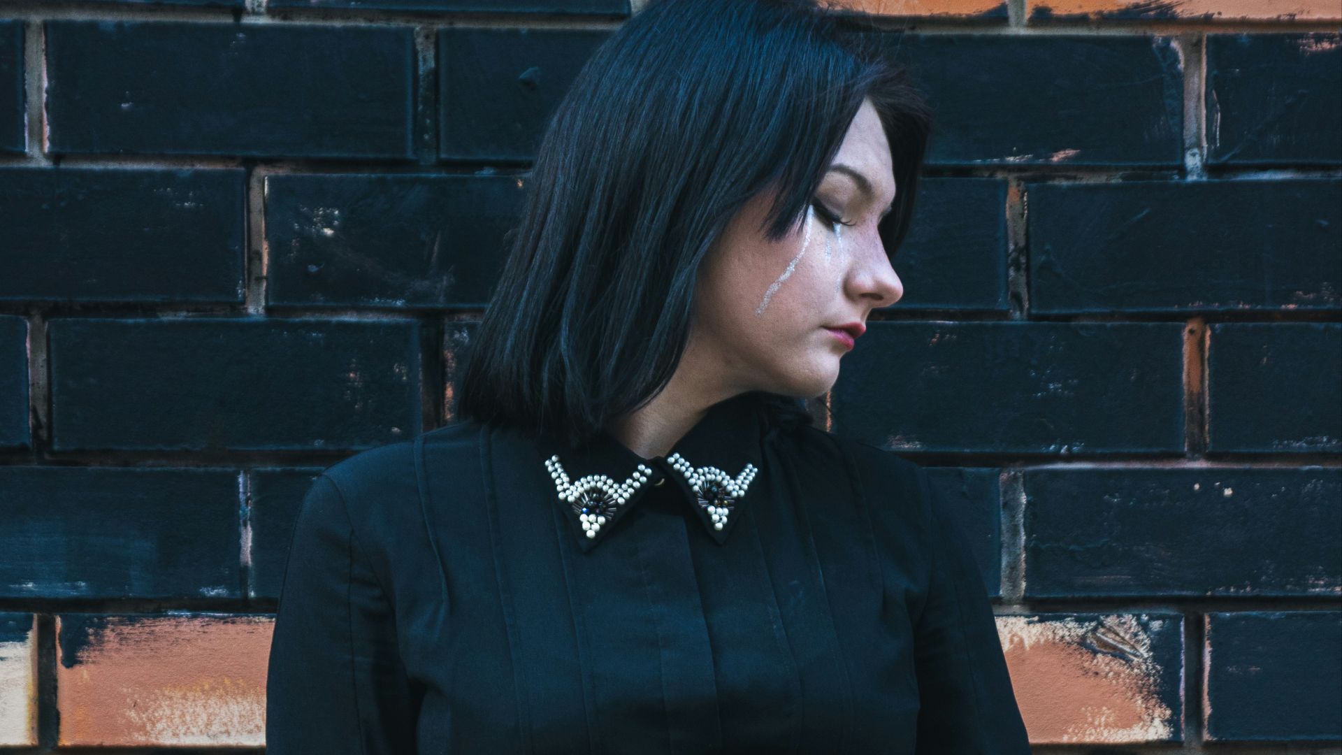 A woman poses in a black gothic outfit.