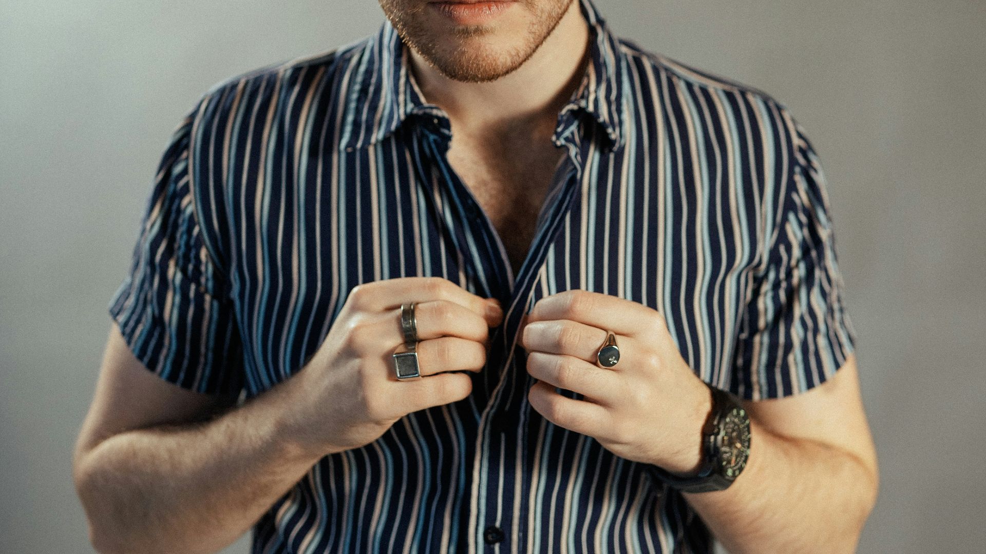 a man in a striped shirt tying his tie