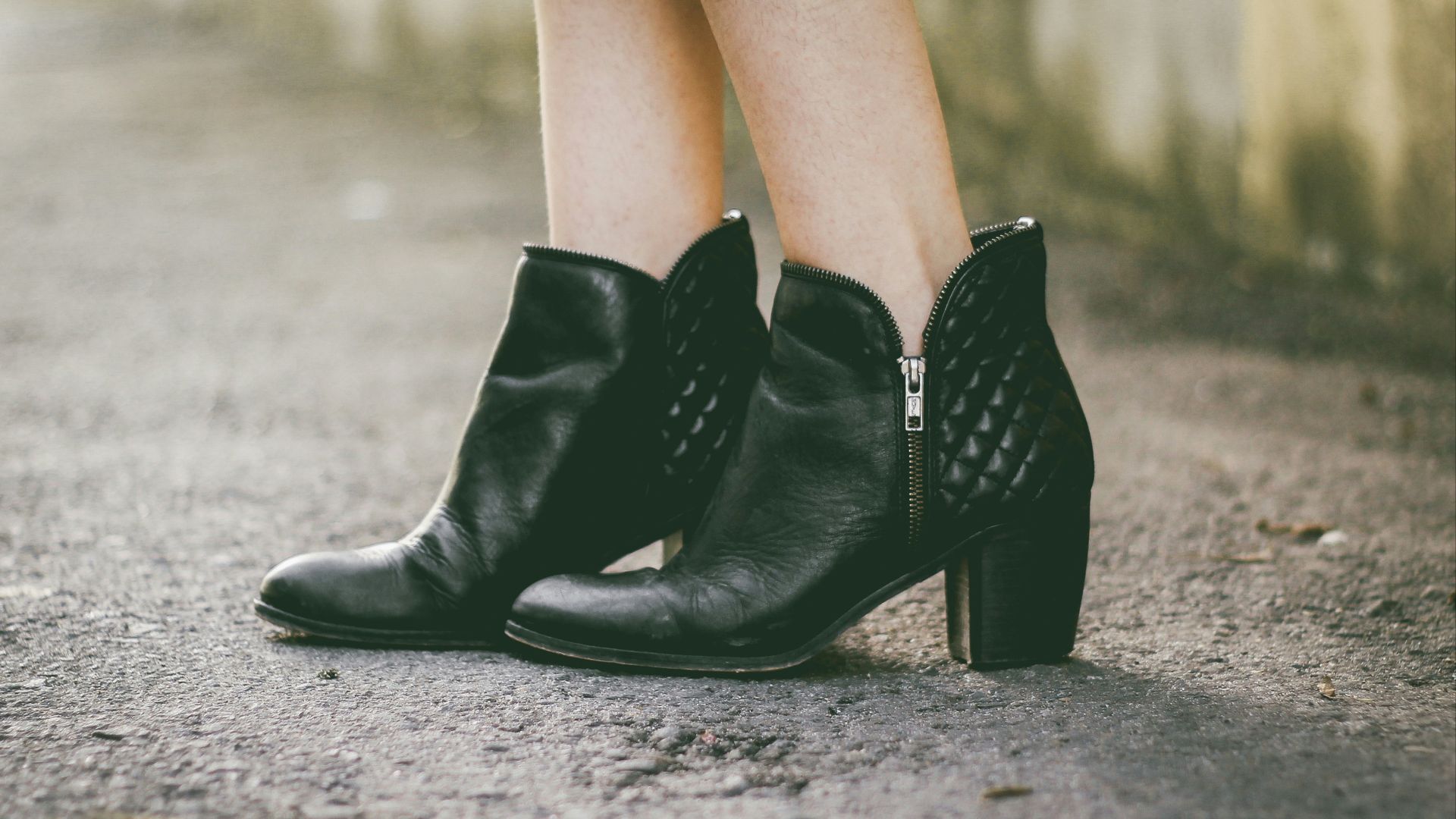 woman in black chunky heels boots standing on gray floor