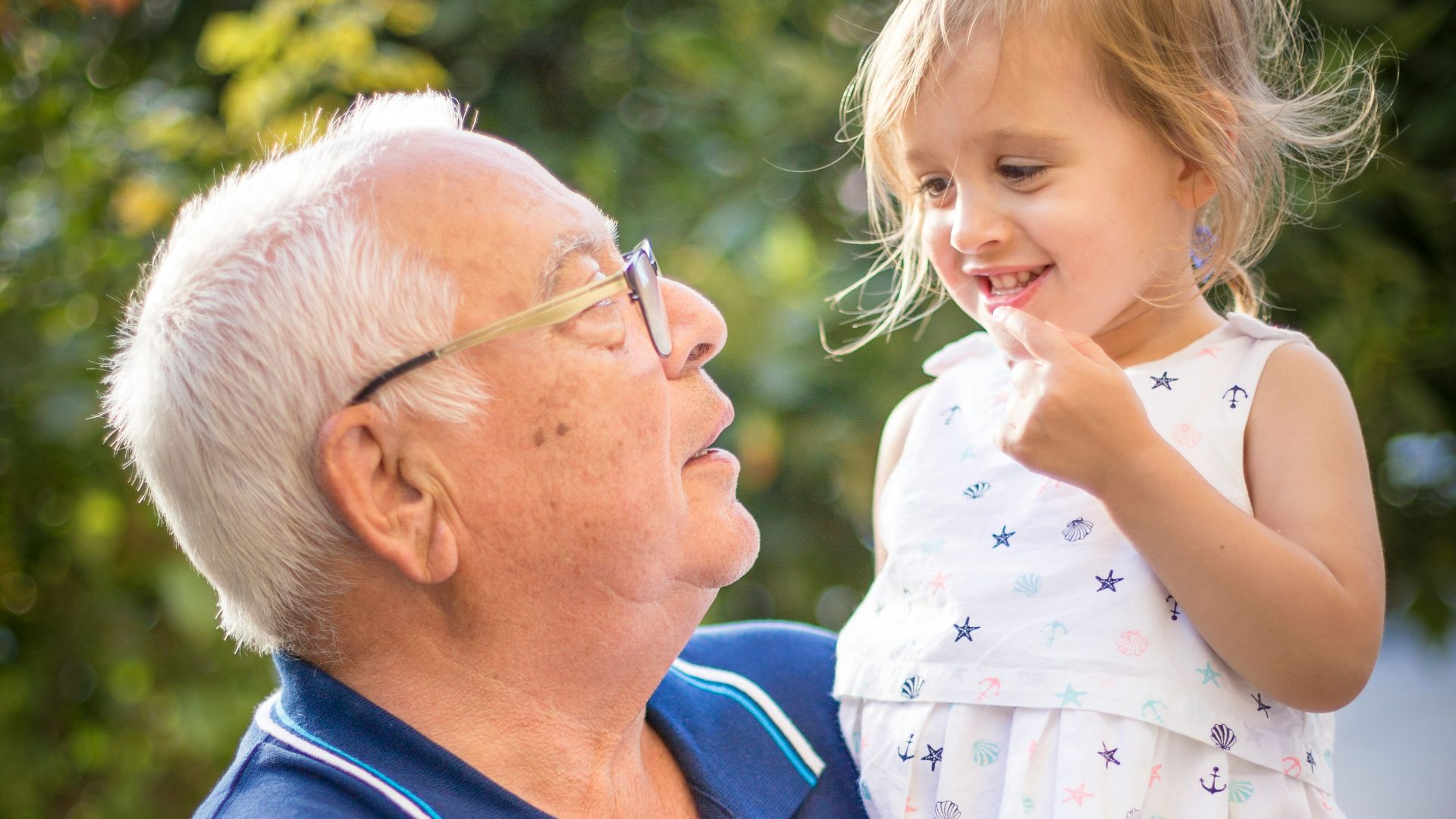 man in blue polo shirt carrying girl in white and pink floral dress