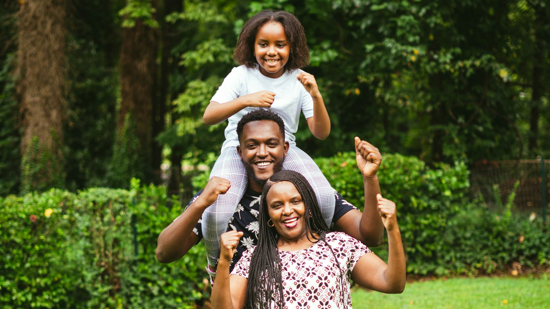 a man and two women holding a child on their shoulders