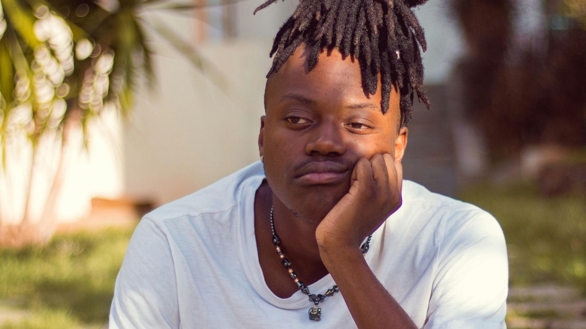 man in white crew neck t-shirt sitting on brown wooden chair