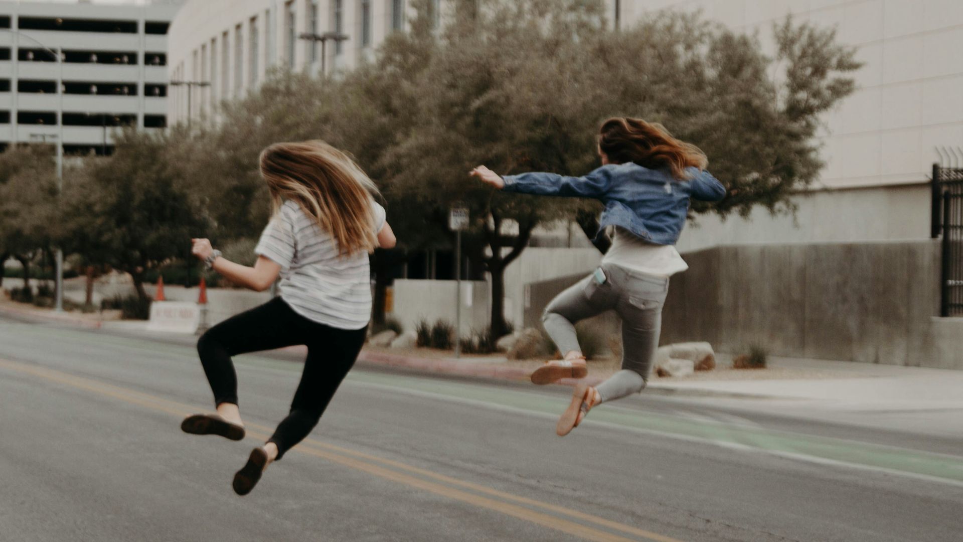 two woman jumping on the street during daytime
