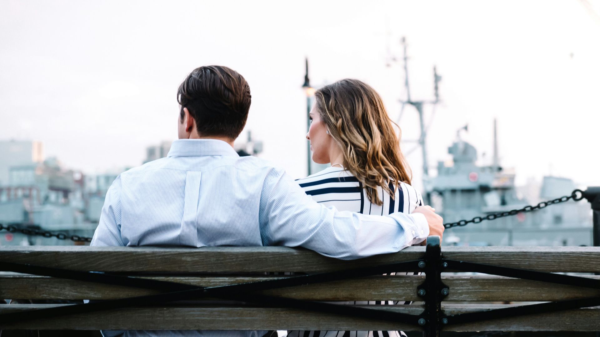 couple sitting on bench near body of water