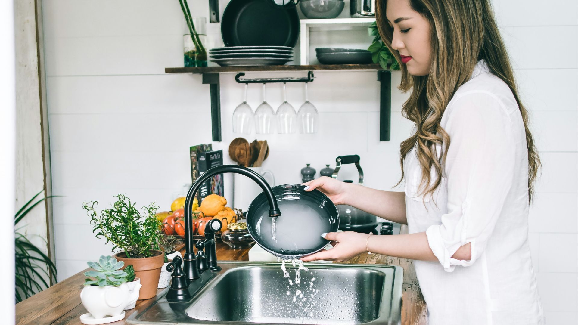 woman wearing white blouse washing dish on the faucet