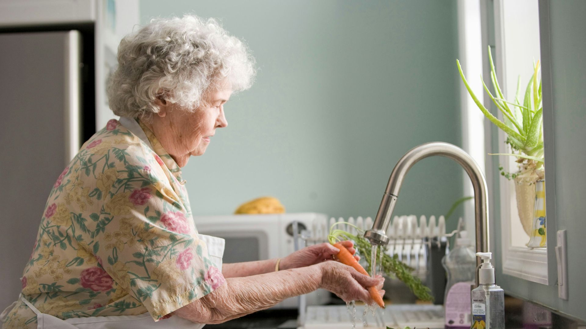 woman in purple and white floral shirt sitting on white bed