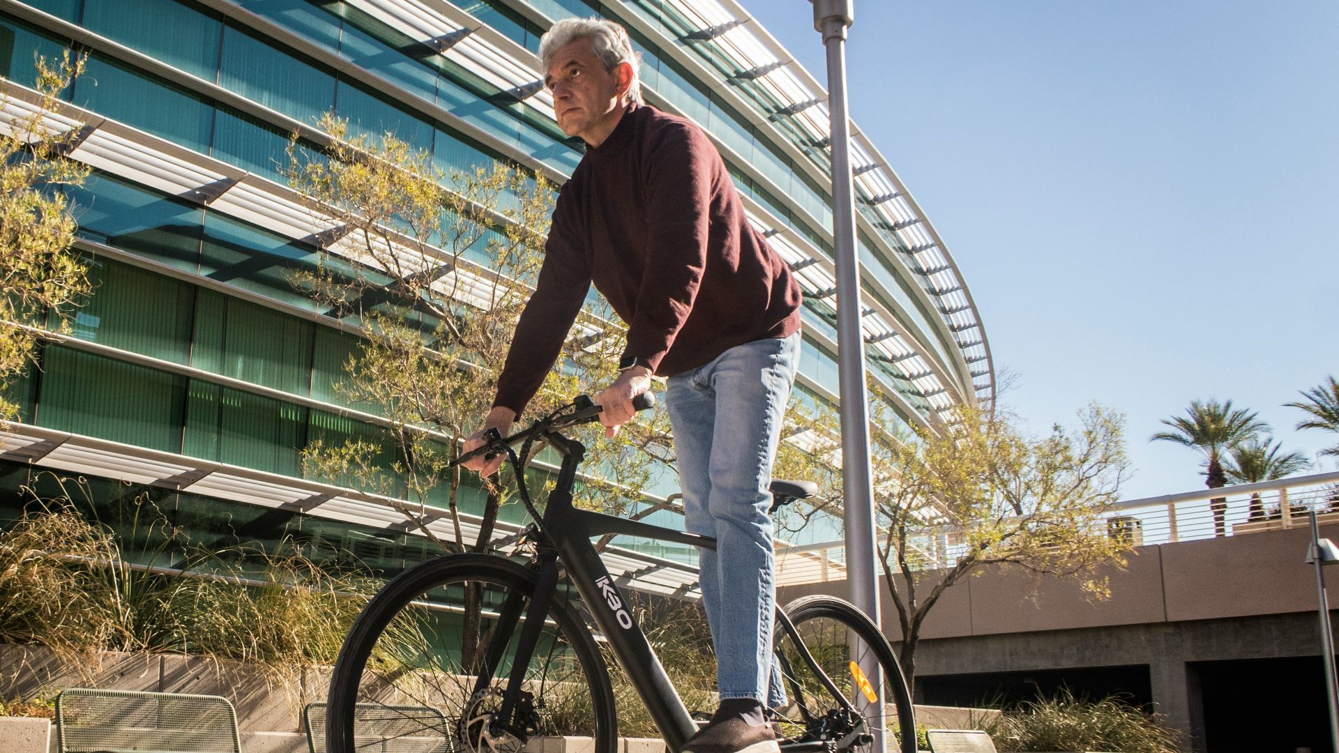 man in red long sleeve shirt and blue denim jeans riding on bicycle
