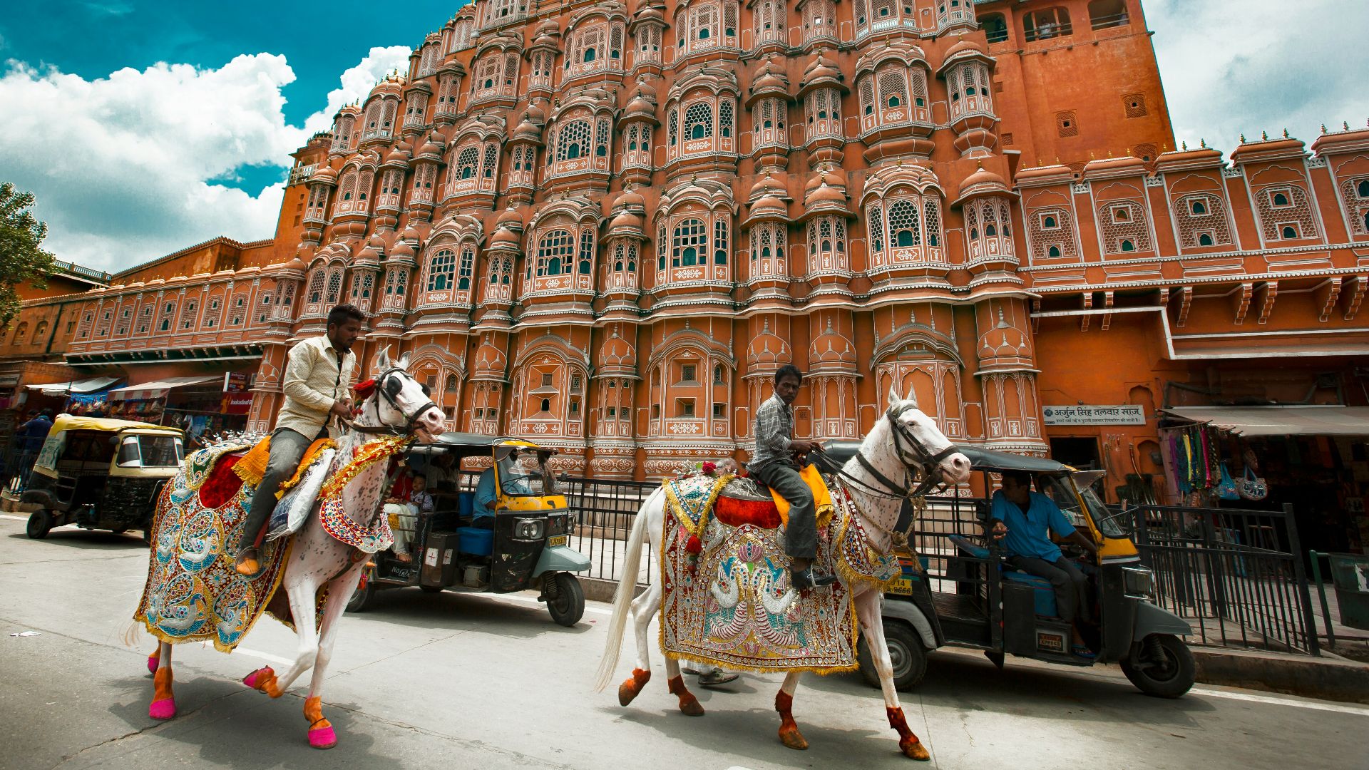 man in white and green long sleeve shirt standing near brown concrete building during daytime