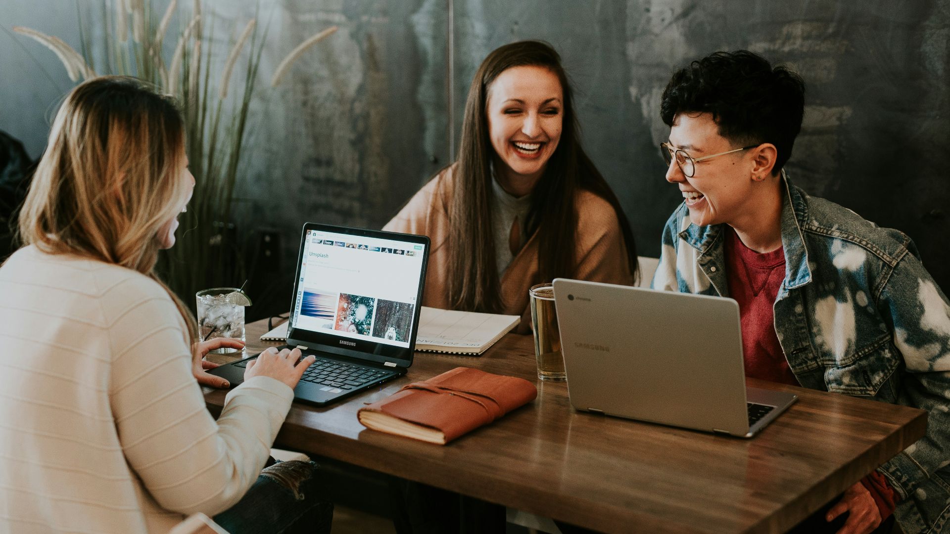 three people sitting in front of table laughing together