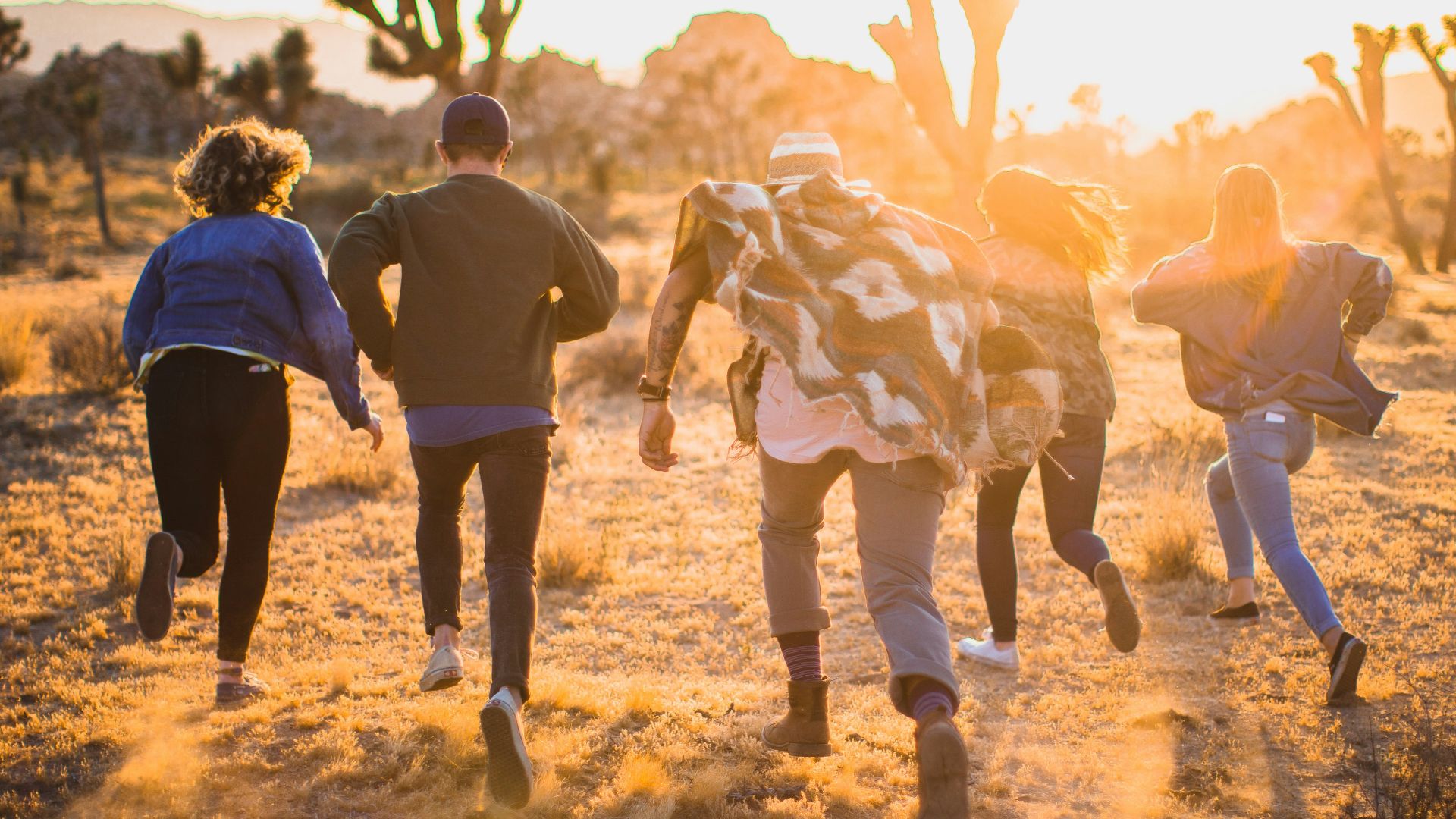 fiver person running on the field near trees