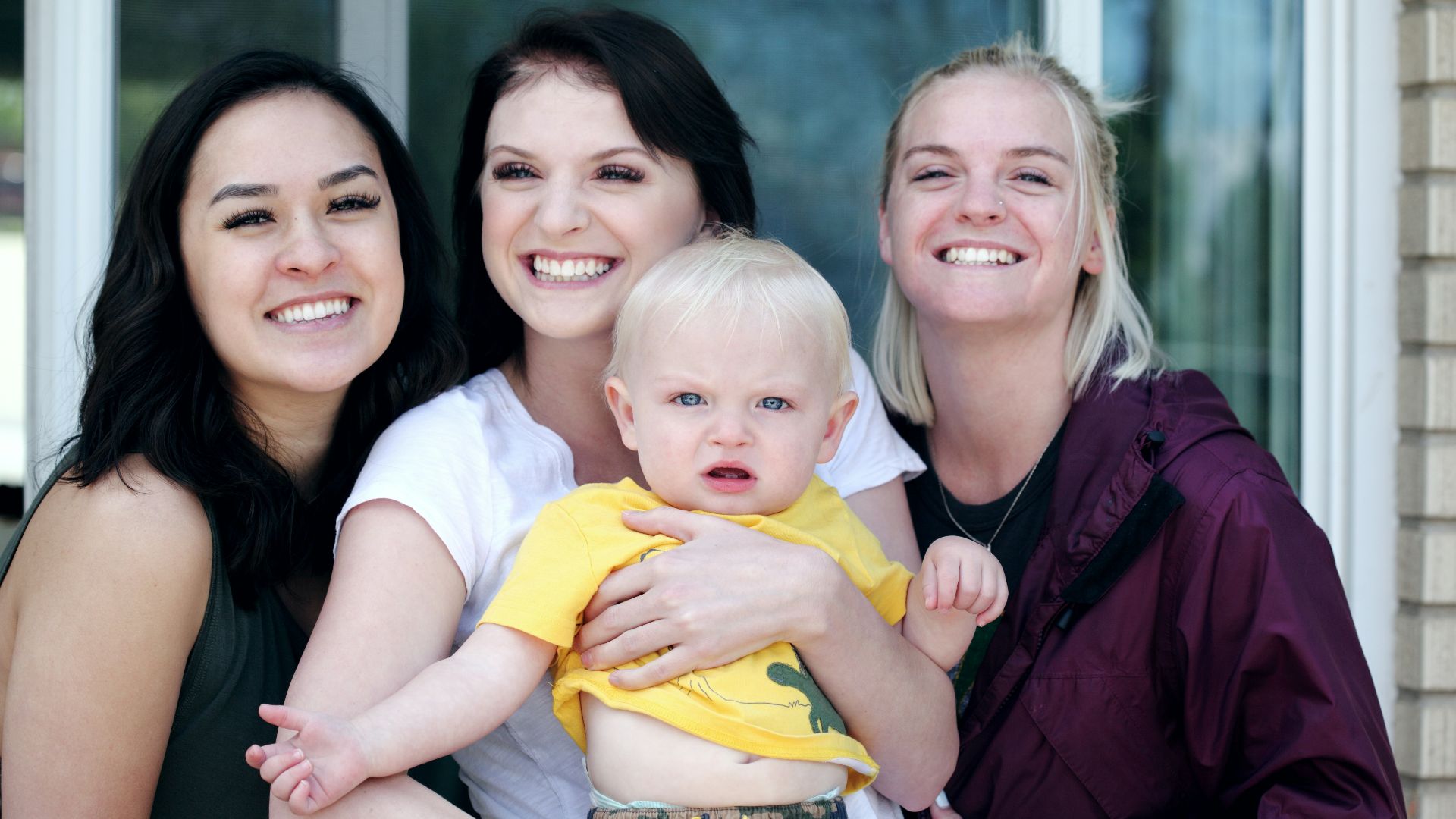 woman carrying baby with two ladies beside her smiling