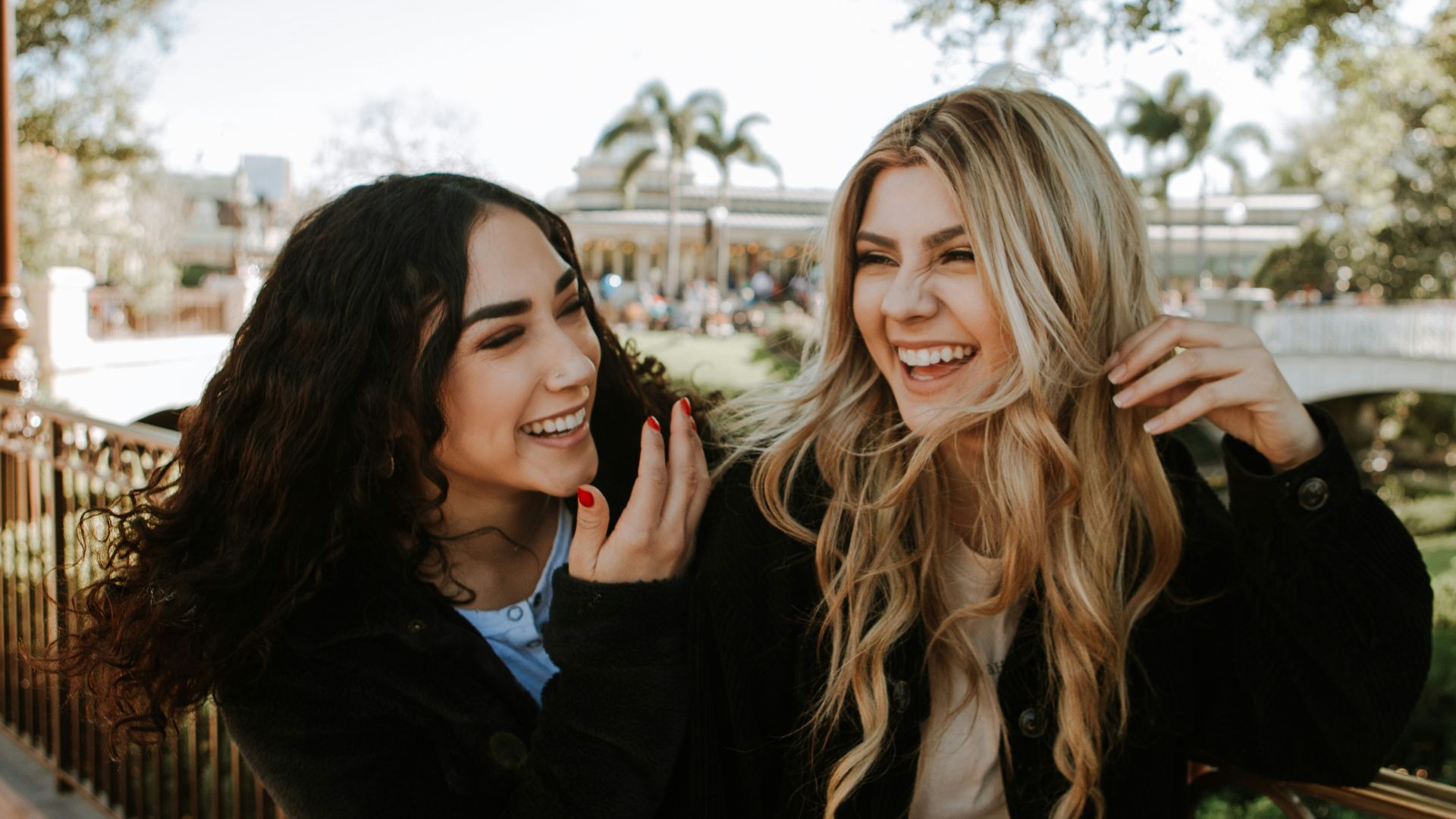 2 women smiling and standing near trees during daytime