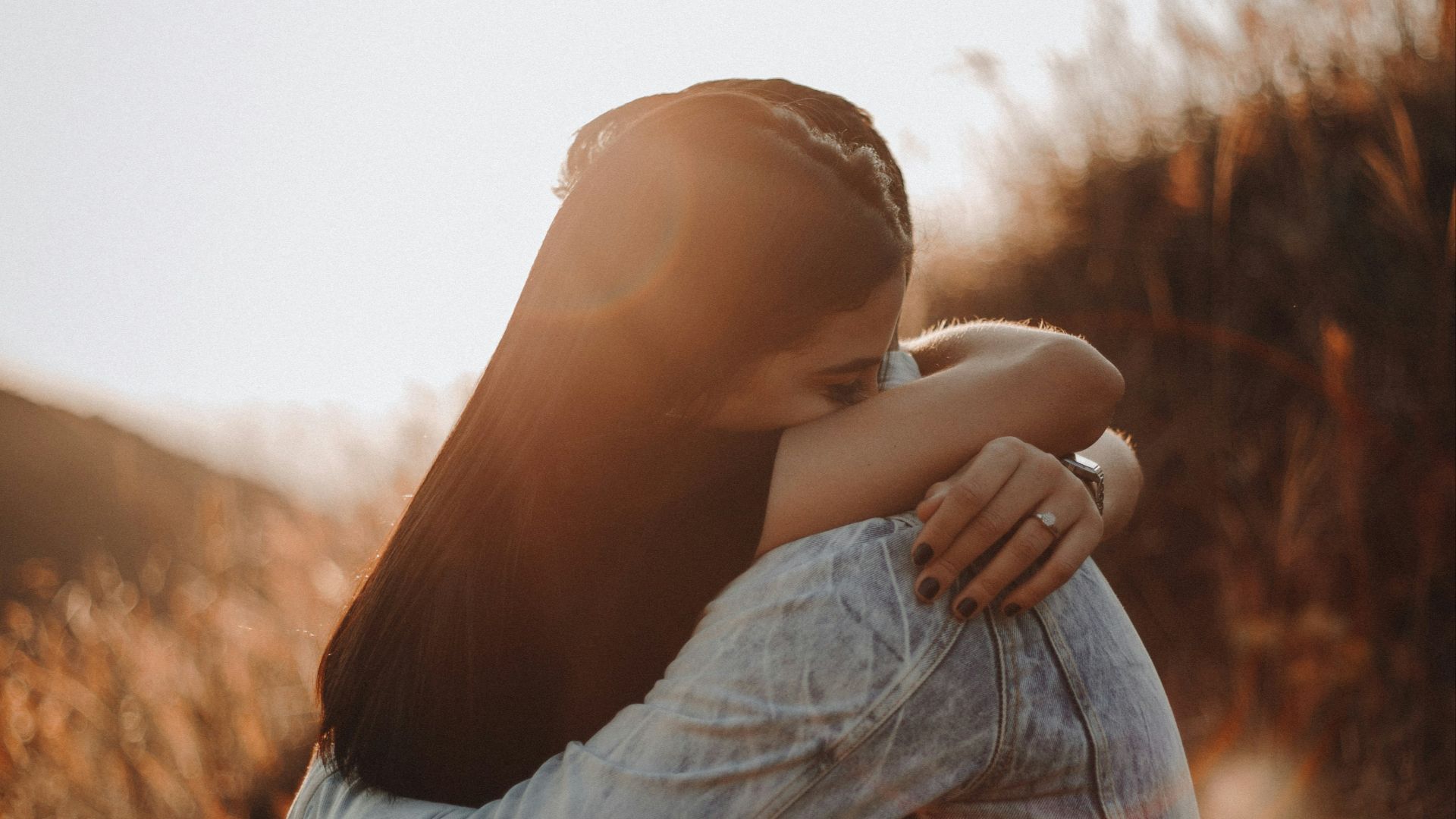 woman in black long sleeve shirt and blue denim jeans covering her face with her hand