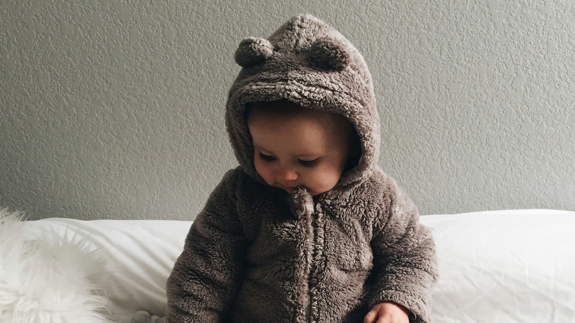 baby seating on white textile