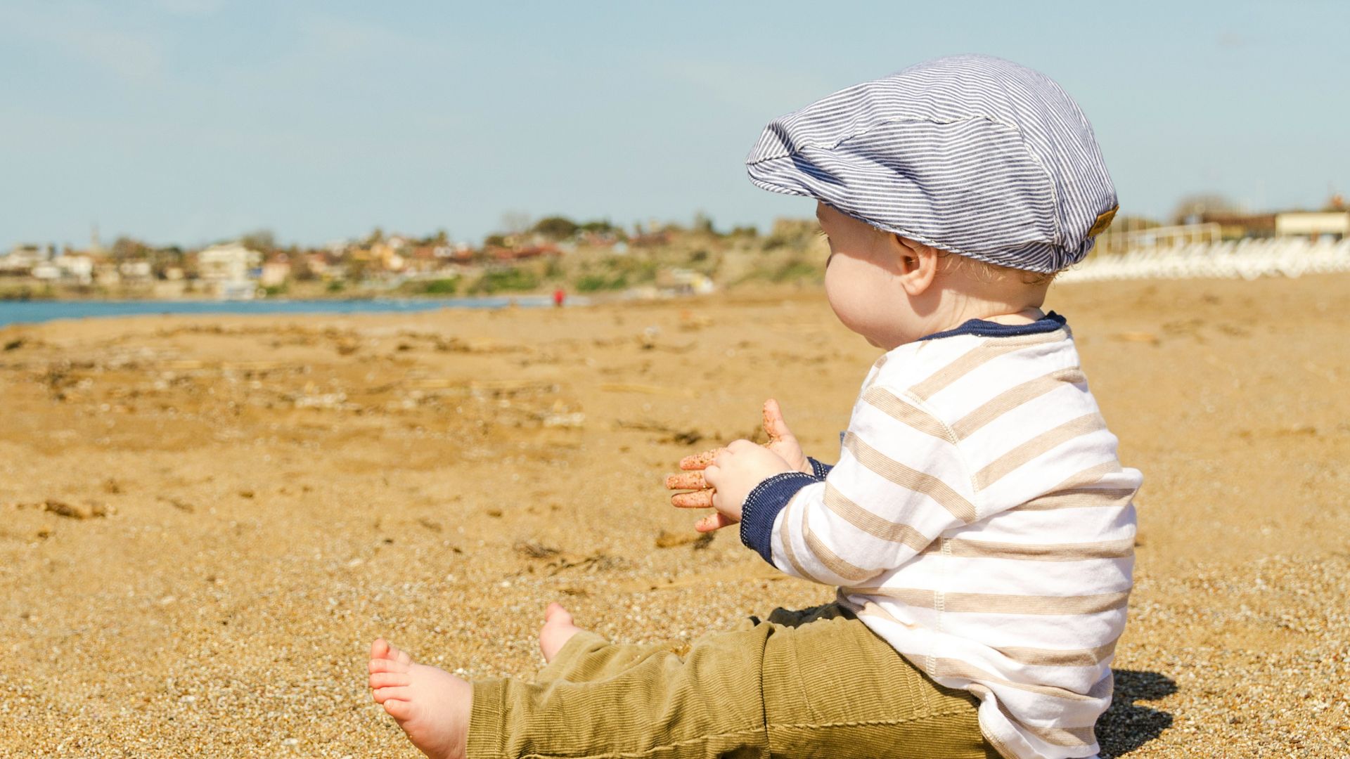 sitting toddler on seashore at daytime