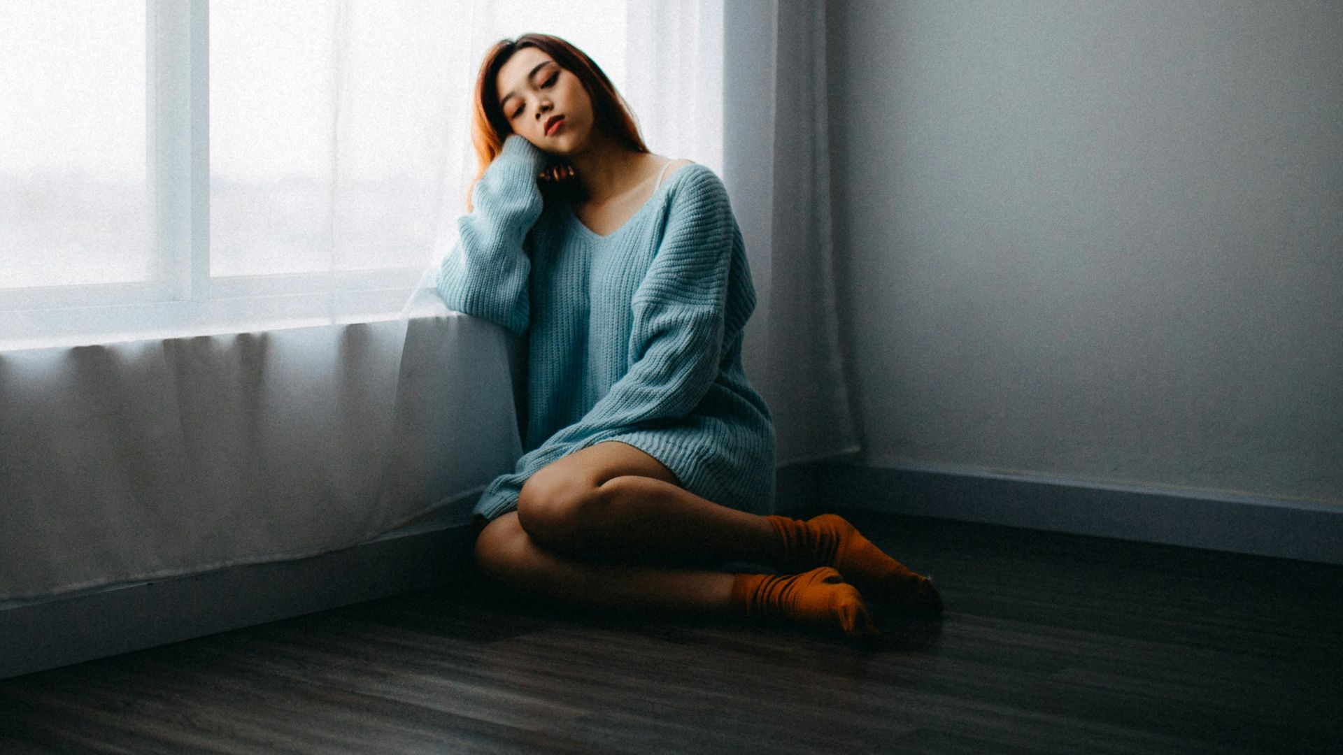 woman sitting on floor near window