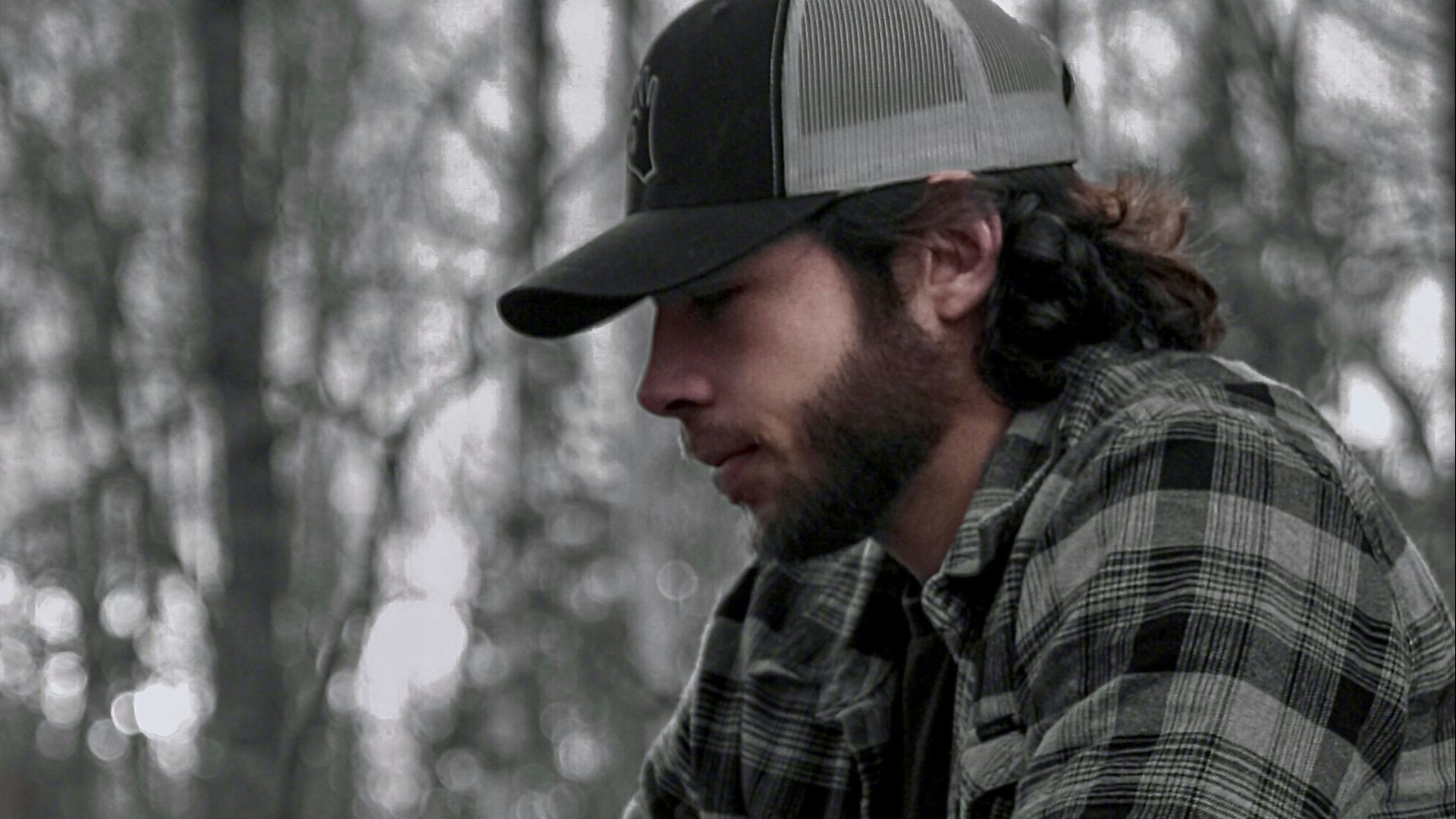 a man wearing a hat sitting on a wooden bench