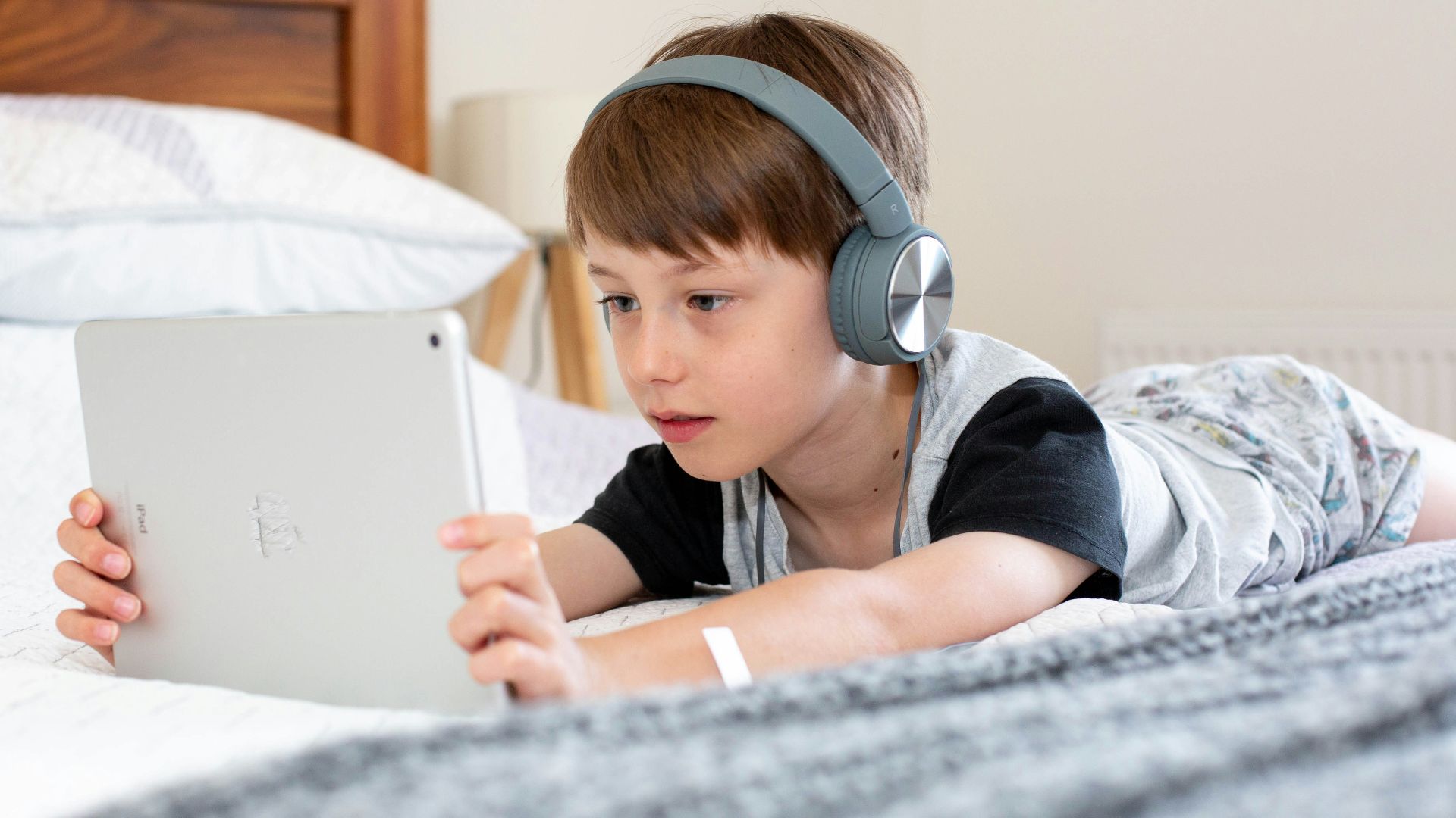 boy in blue shirt wearing headphones lying on bed