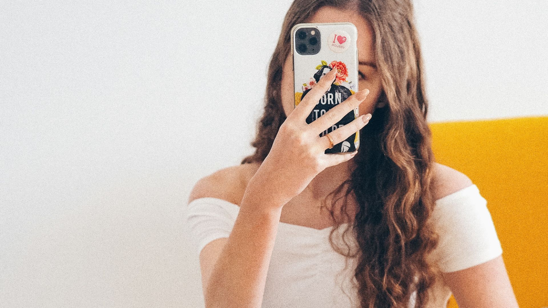 woman in white tank top and blue denim jeans sitting on yellow chair