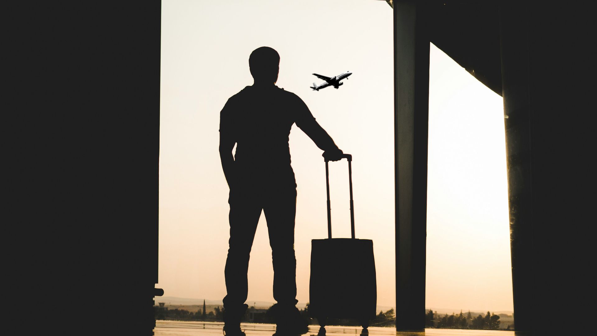 silhouette of man holding luggage inside airport