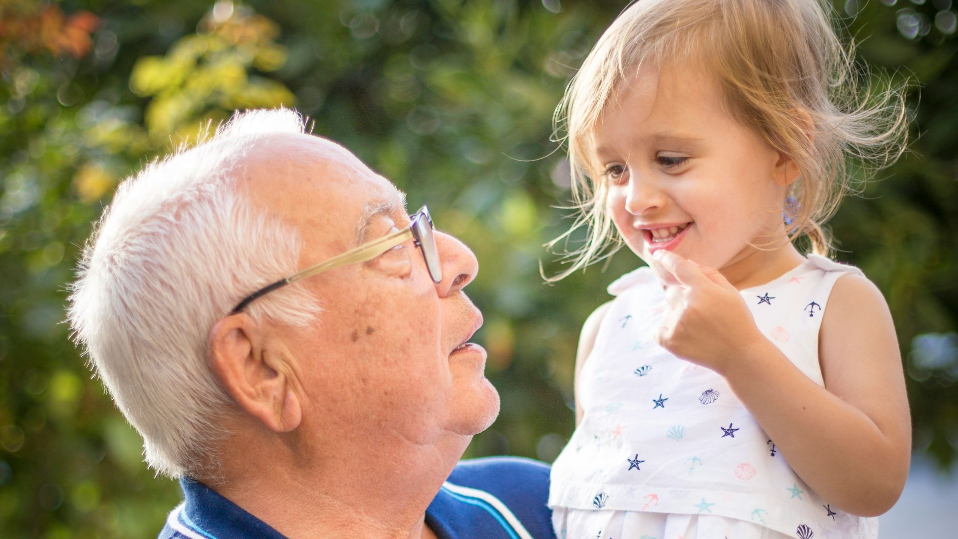 man in blue polo shirt carrying girl in white and pink floral dress