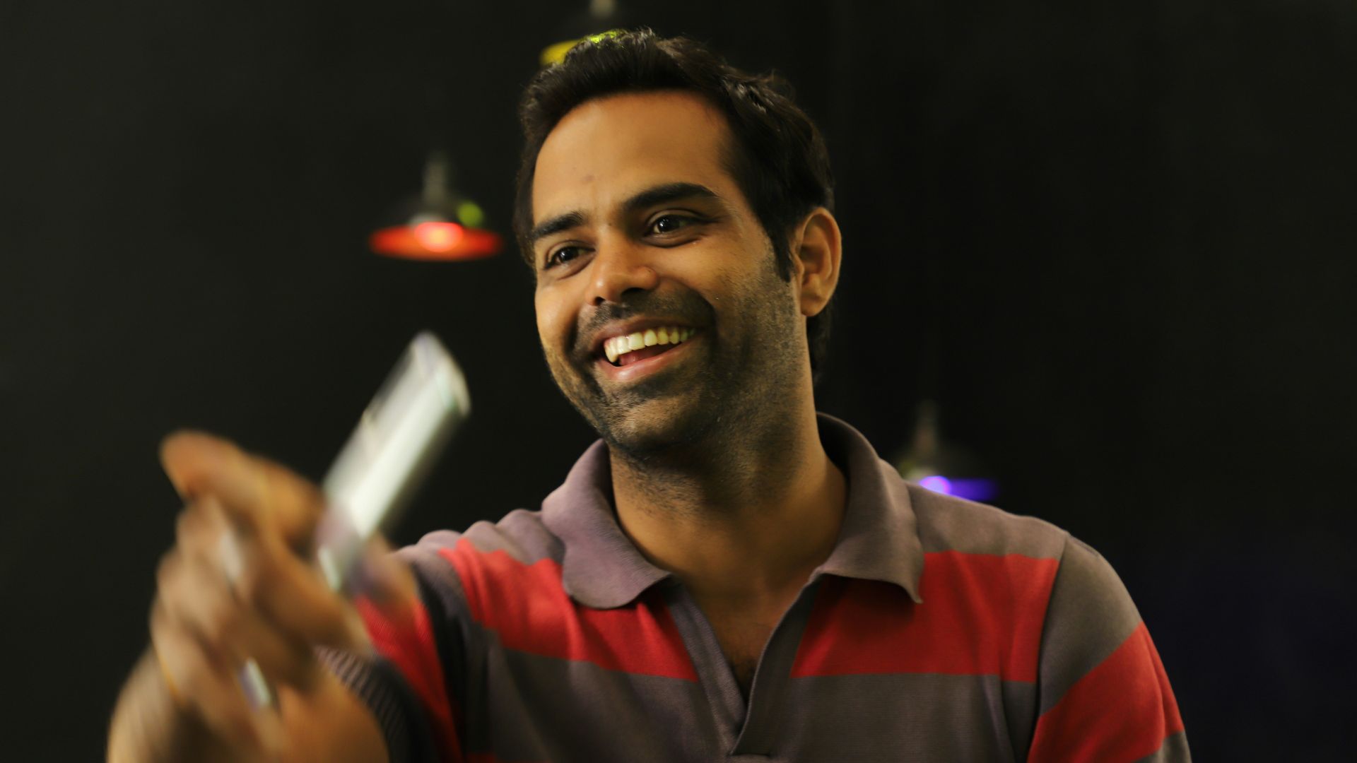 man in red and black v neck shirt holding white cigarette stick
