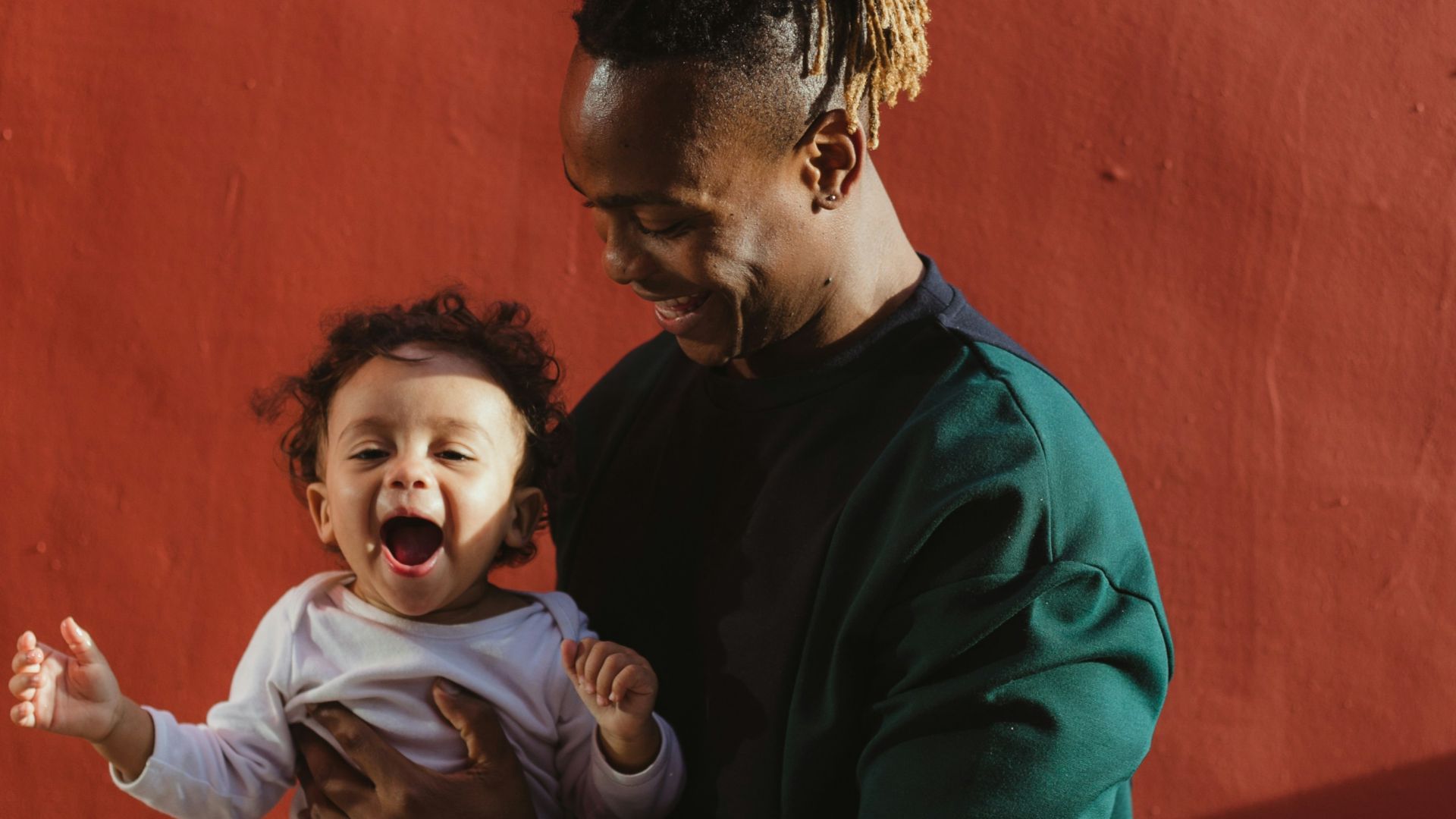 smiling man carrying child and playing