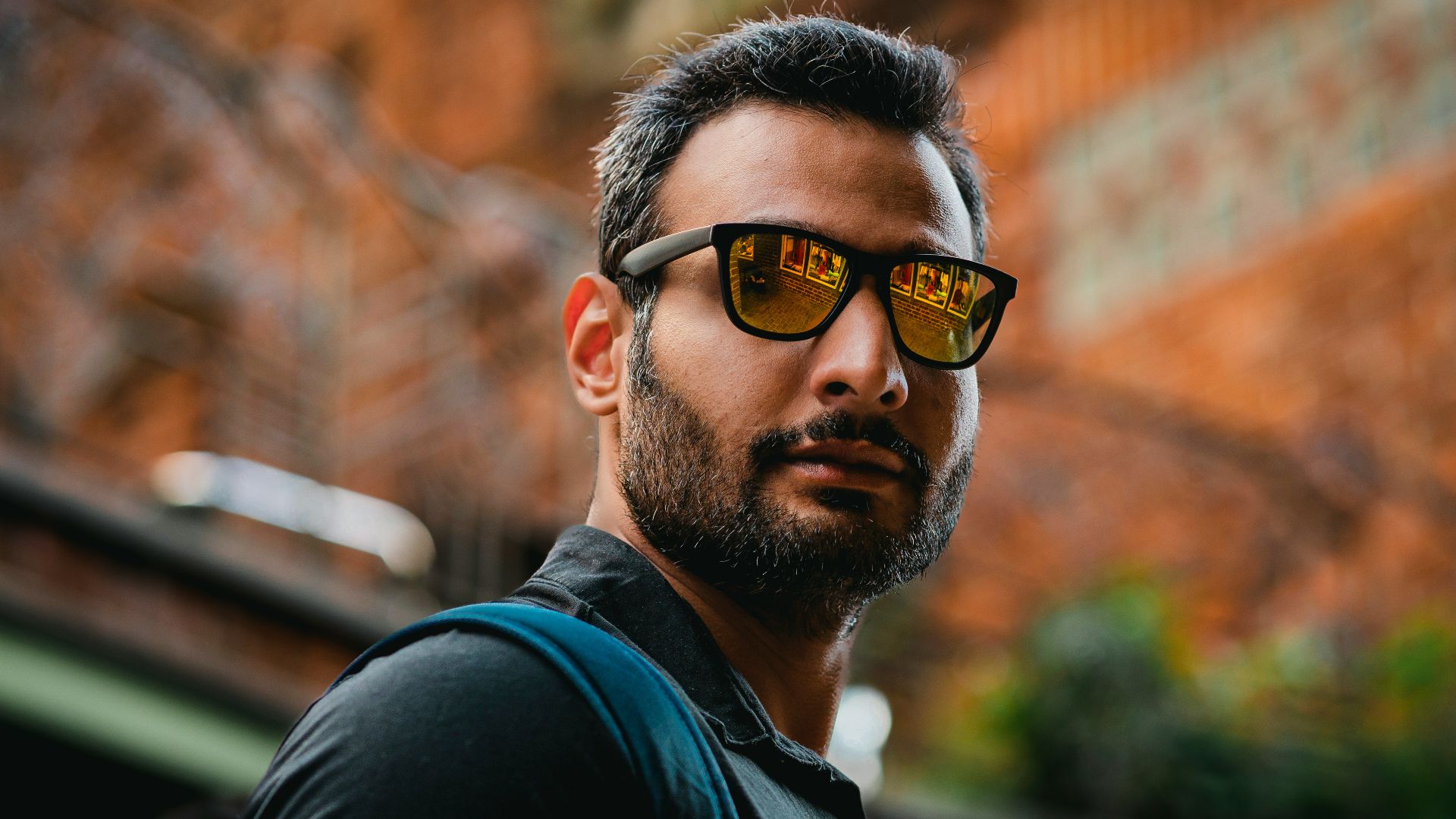 A man with a beard wearing sunglasses and a backpack