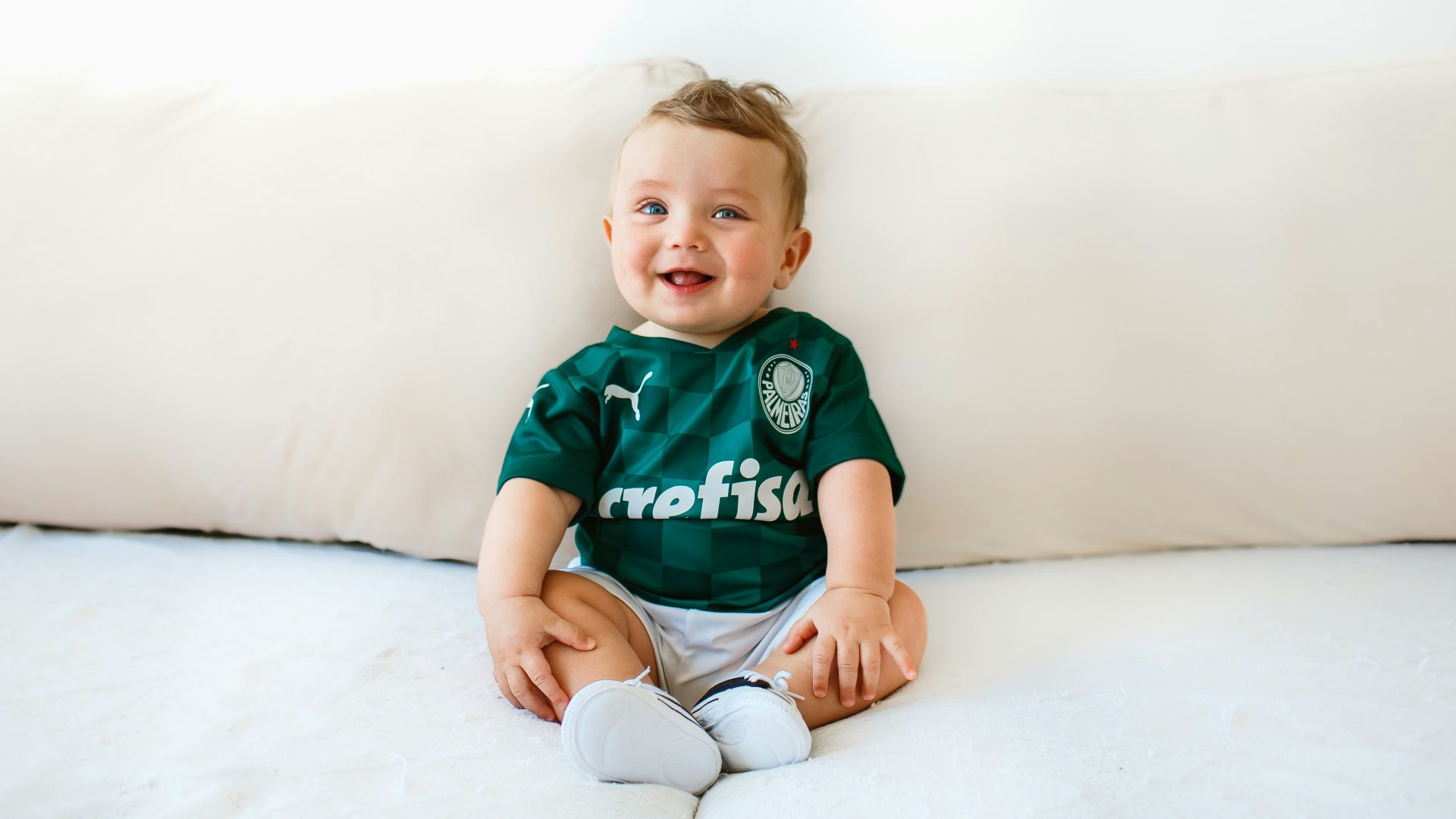 boy in green and white crew neck t-shirt sitting on white bed